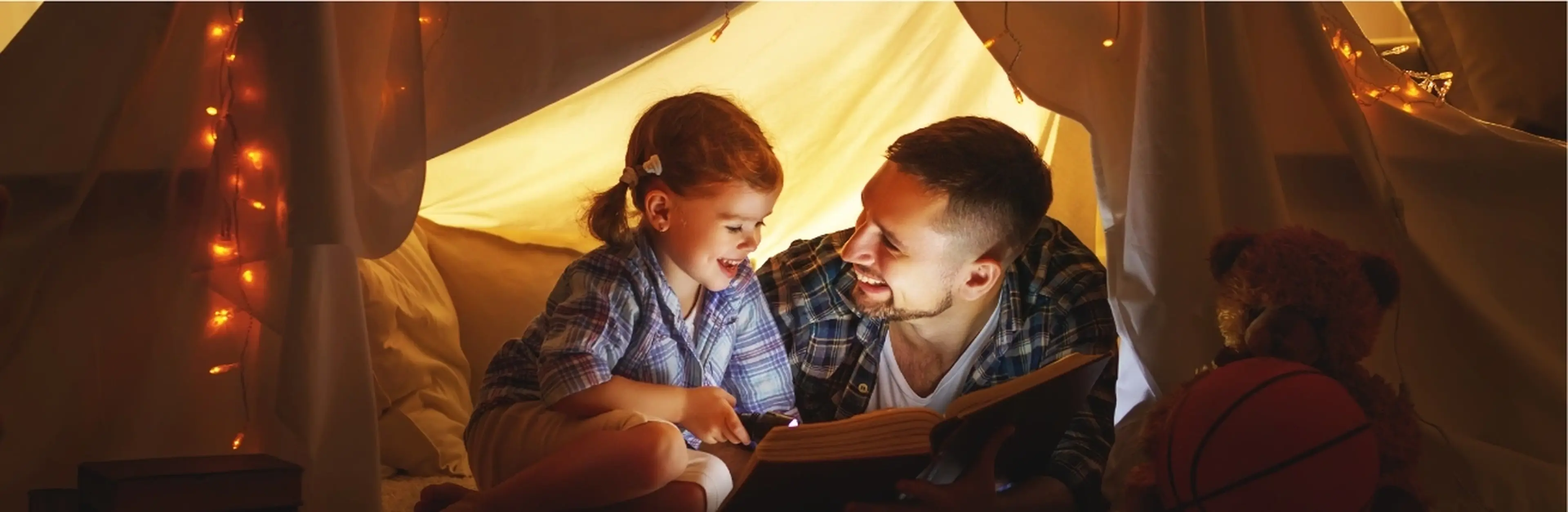 An image of a father and daughter reading a book together