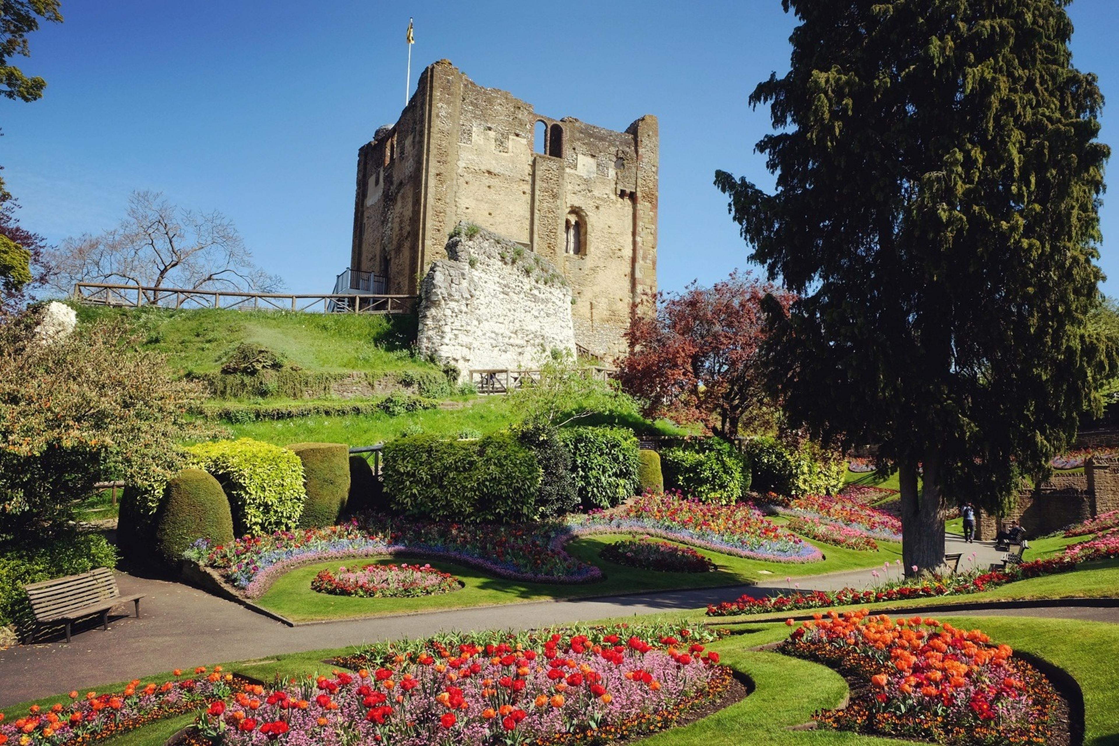 Ancient castle with a stone tower surrounded by vibrant flower gardens