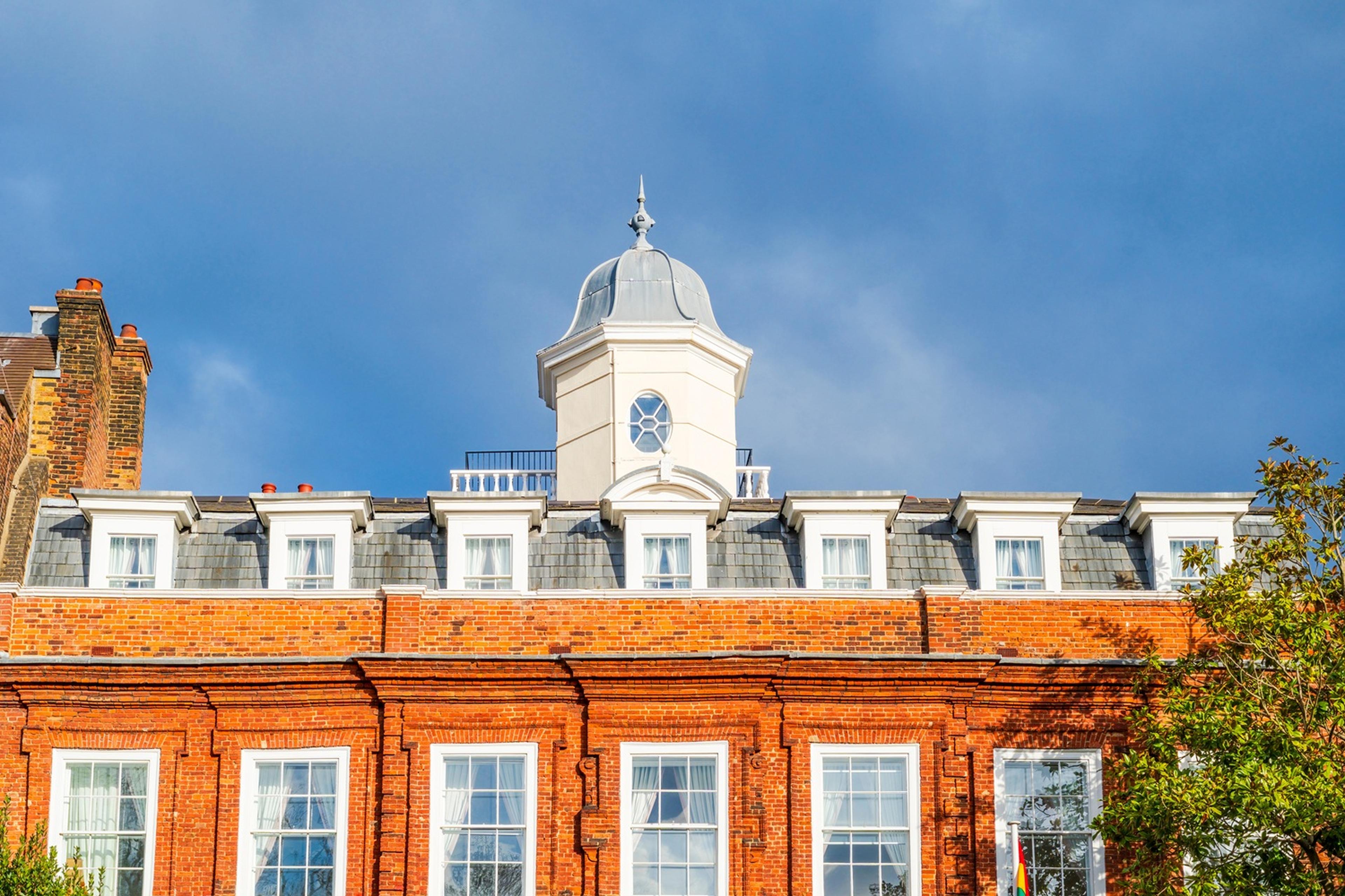 Red brick building with white dormer windows and a central cupola in North London