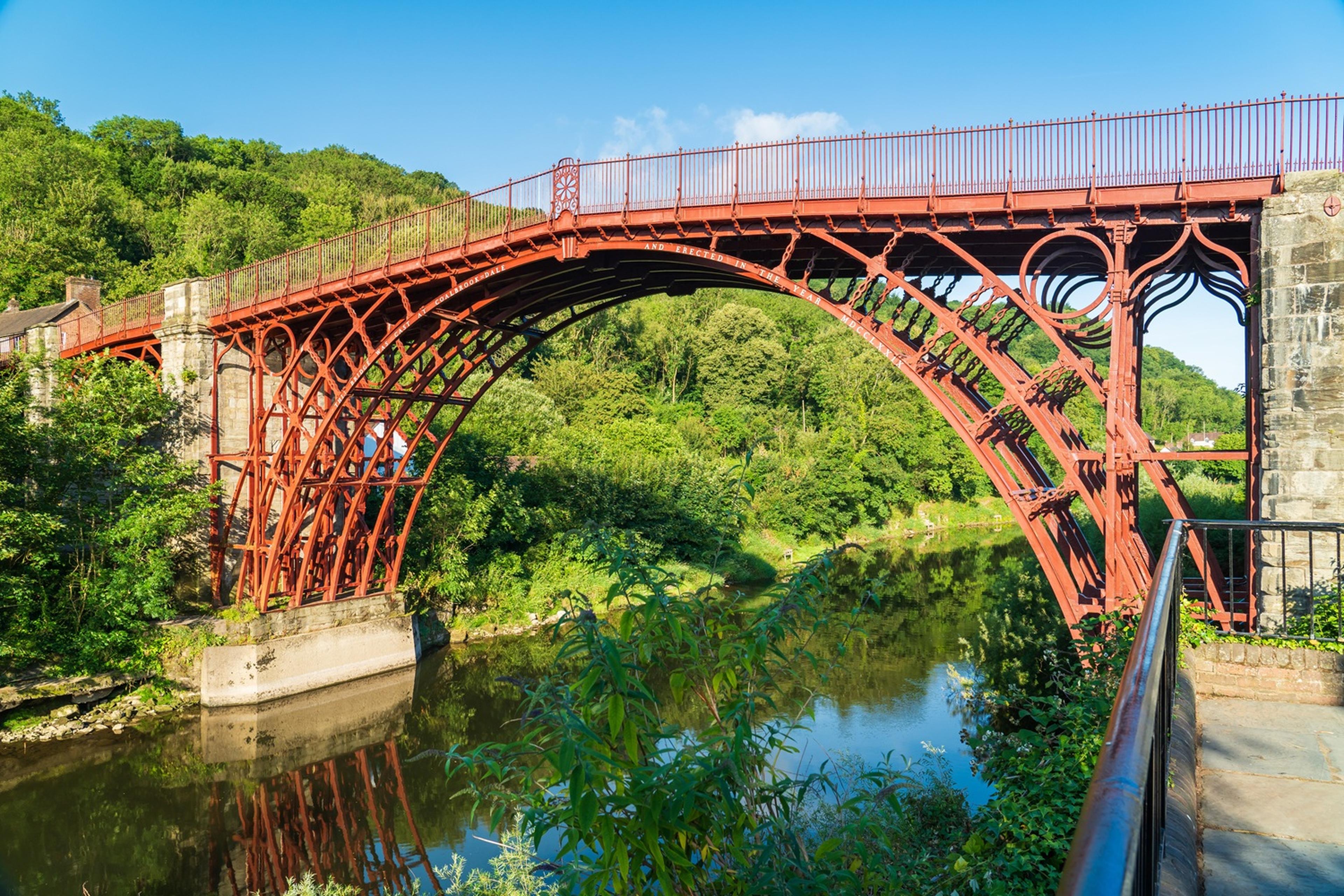 Red iron bridge spans over a river