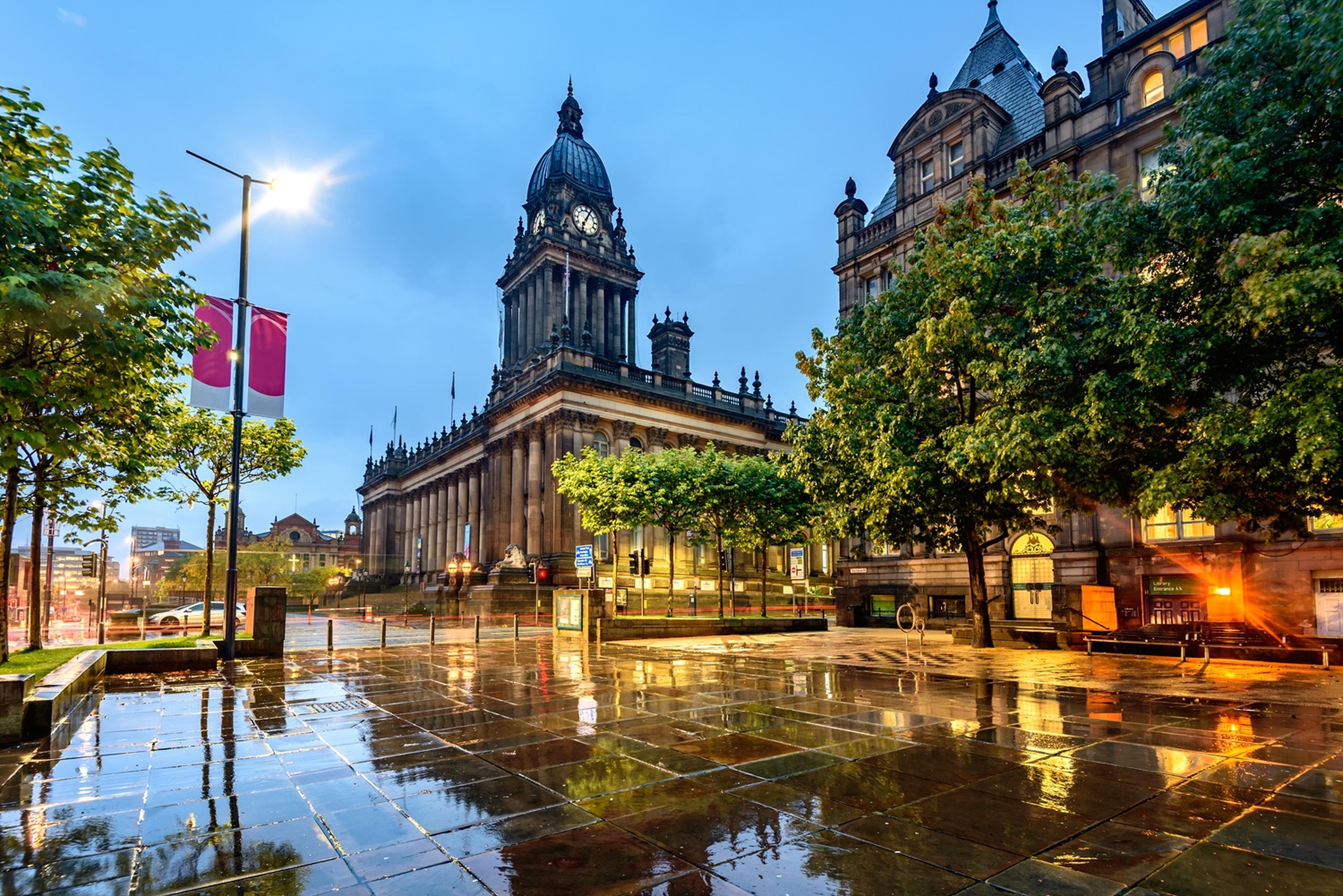 Illuminated historic building in a rainy plaza at dusk