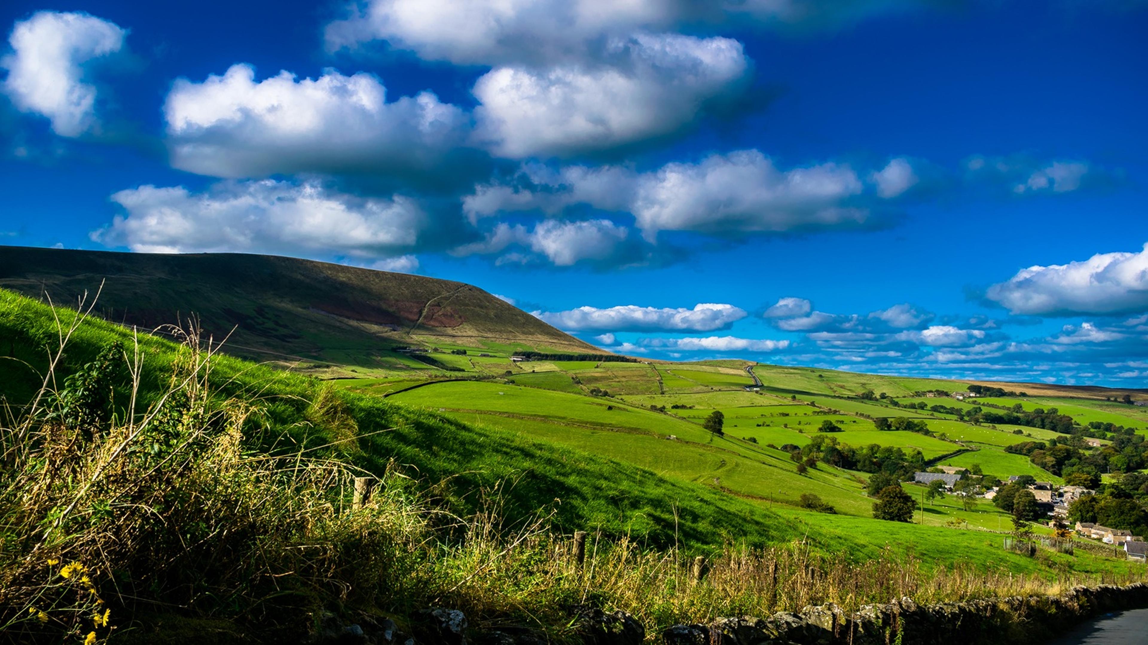 A lush green hillside with a small village in Pendle