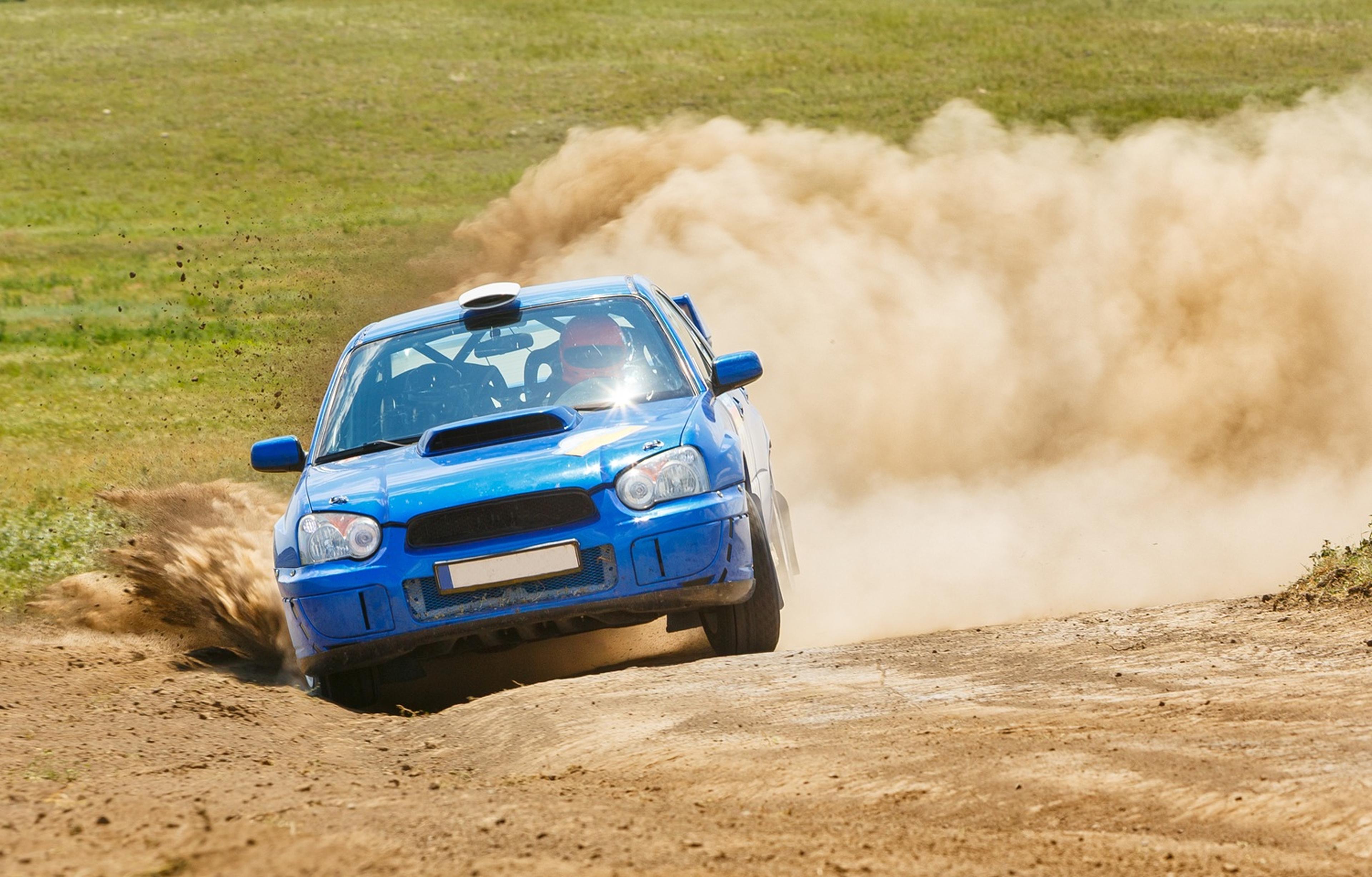 Blue rally car speeding on a dirt track