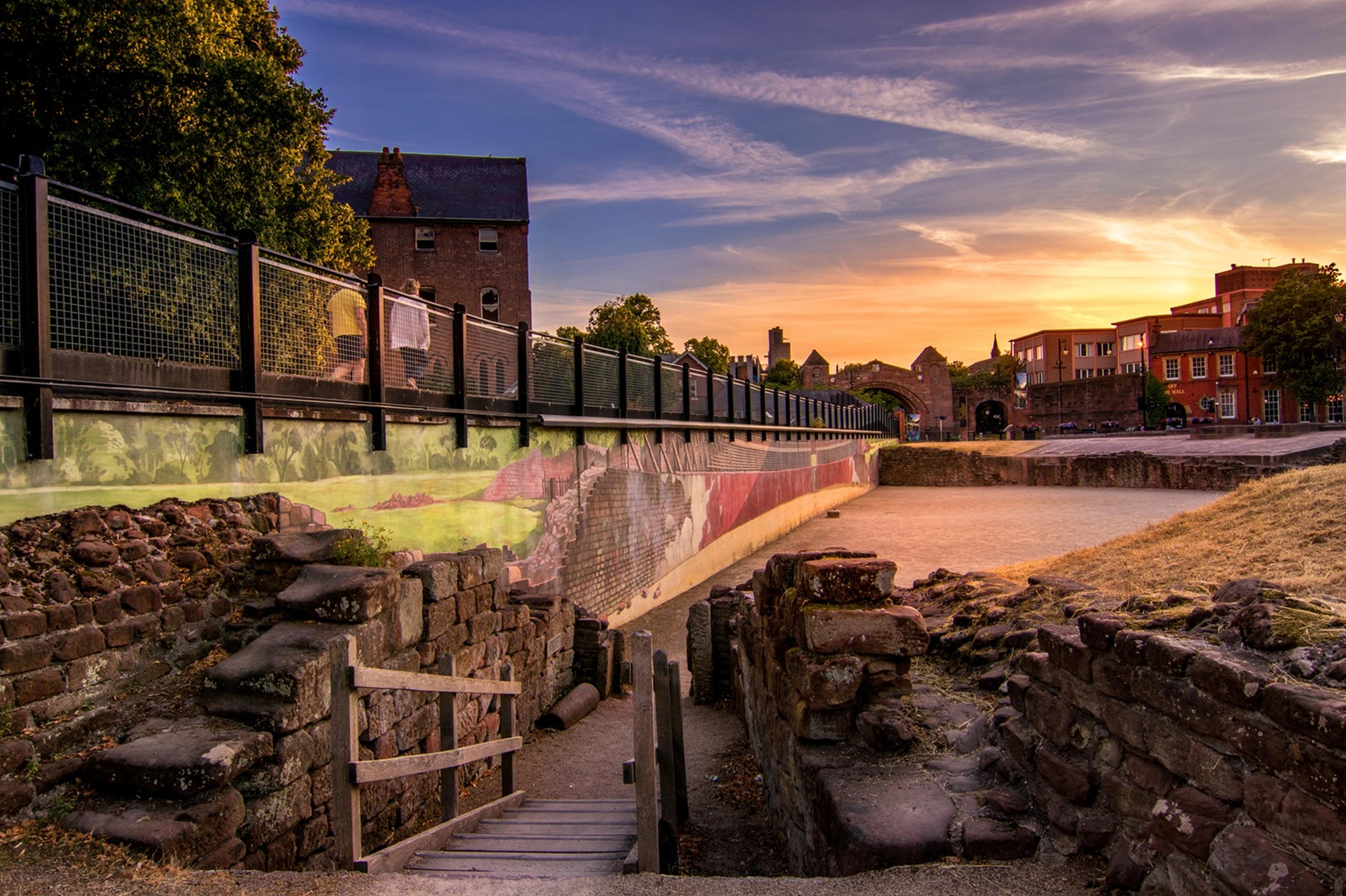 A picturesque sunset over a historic stone wall and walkway