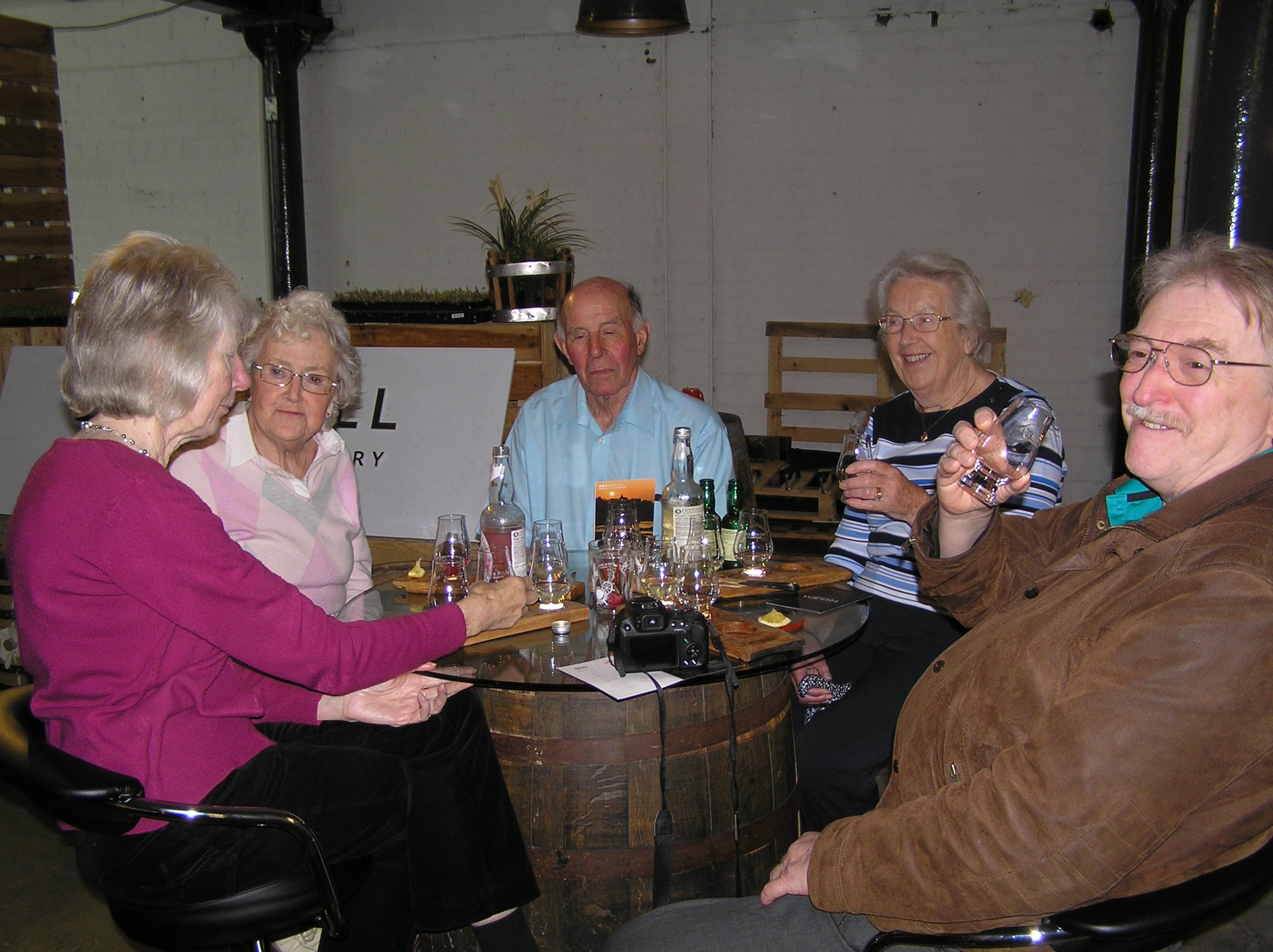 Five people sitting around a glass table, enjoying drinks and chatting