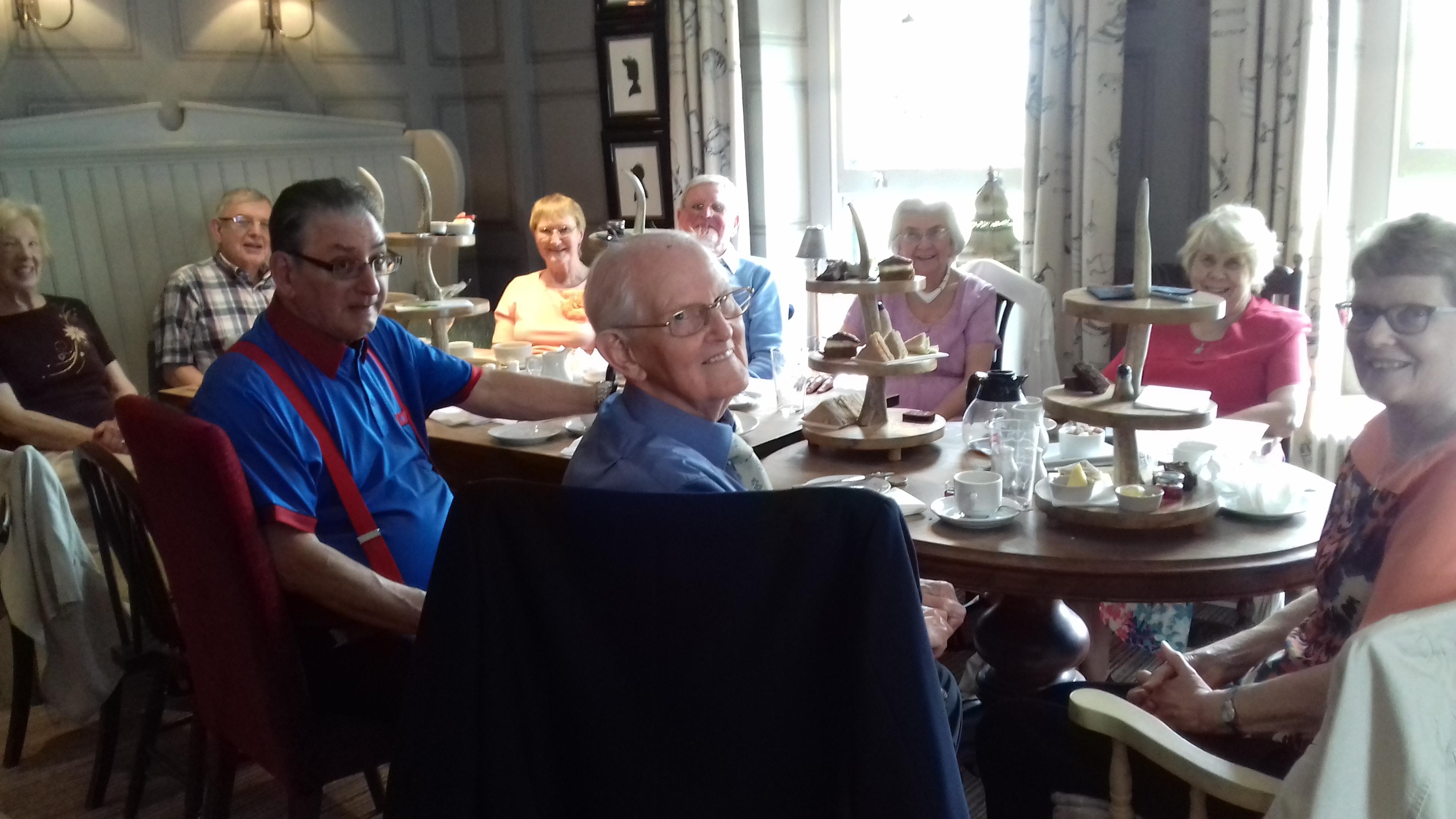 A group of elderly people enjoying afternoon tea at a warmly lit café