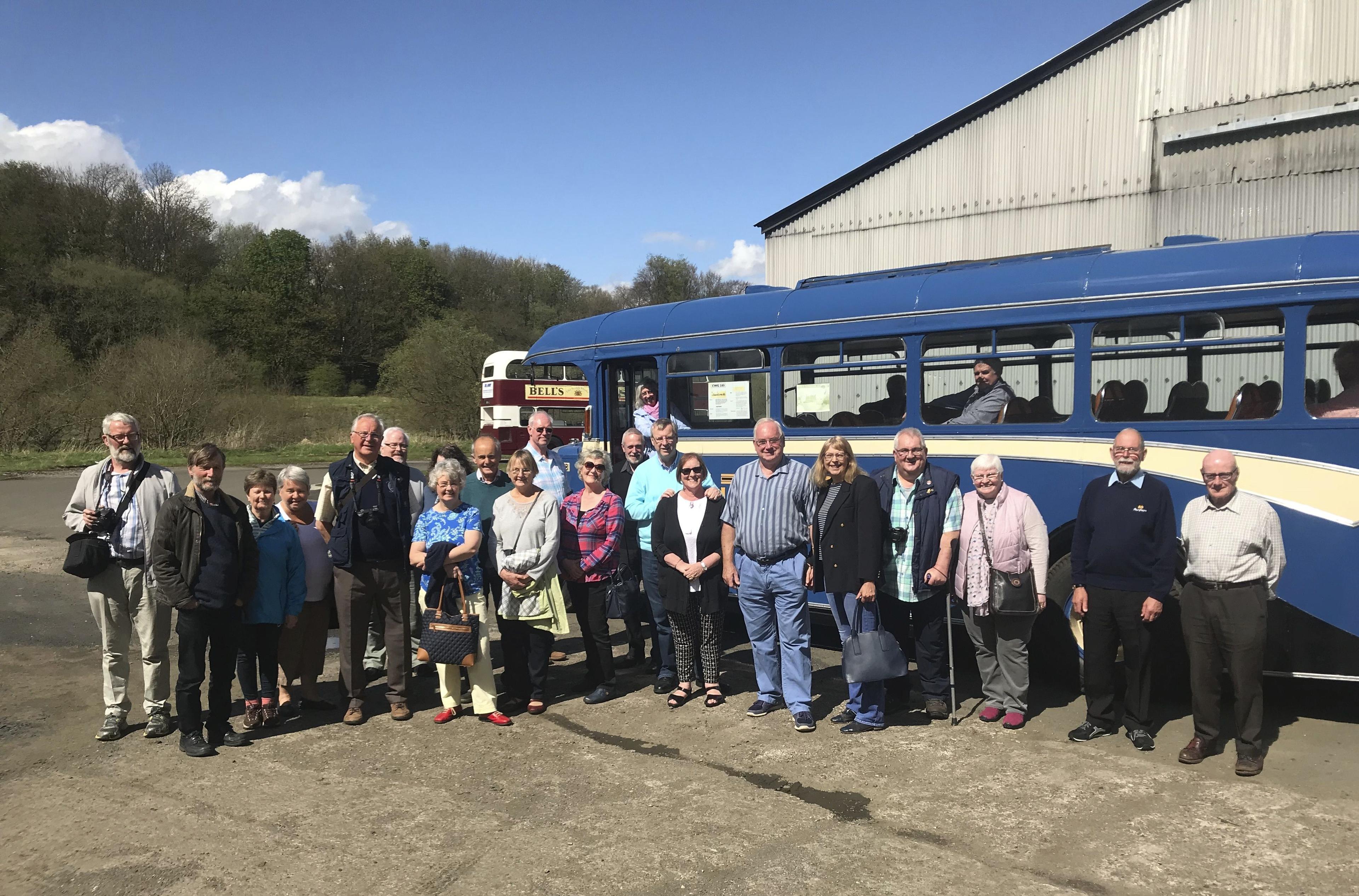 A group of people standing outside a vintage blue bus