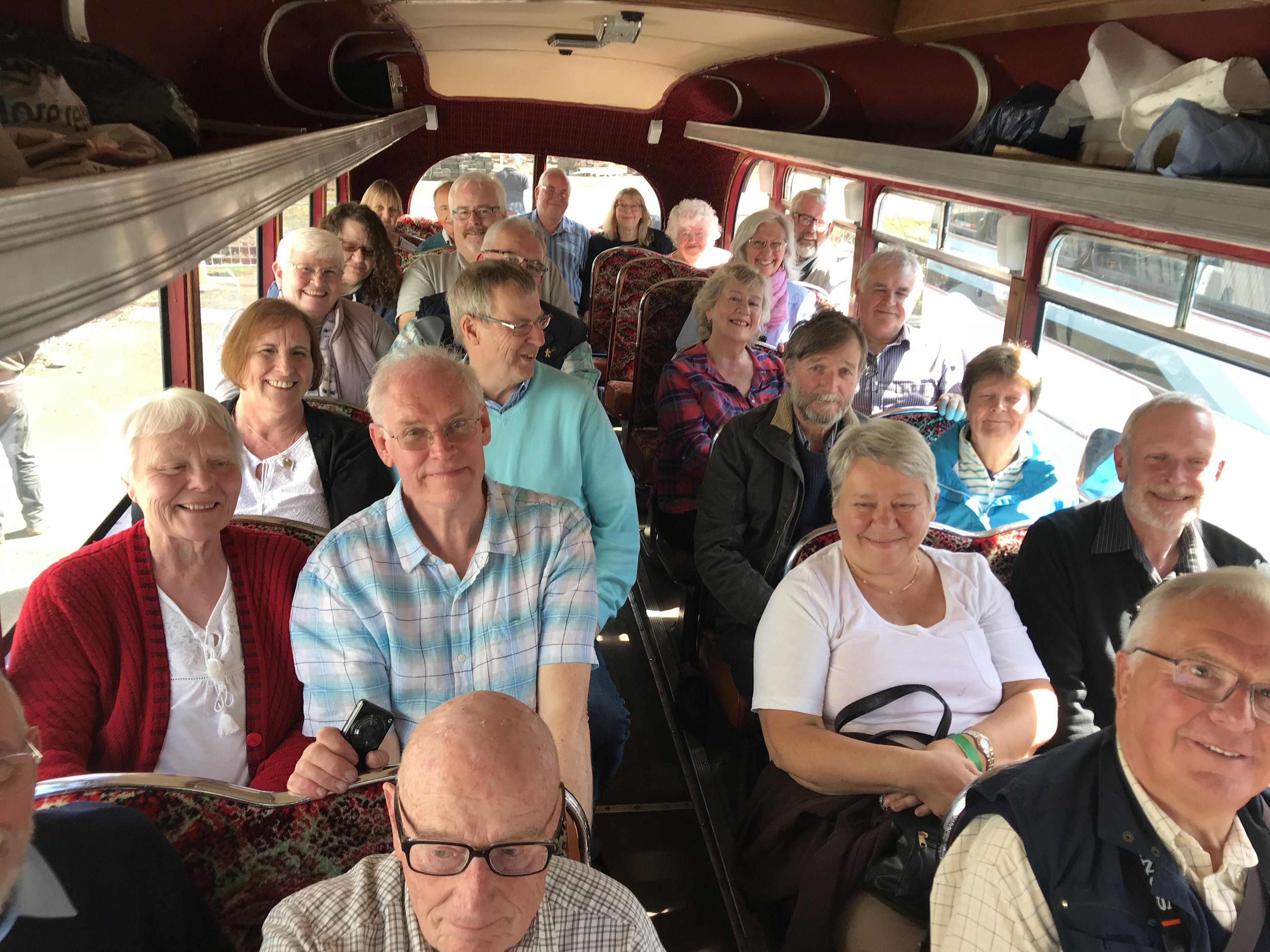 A group of smiling older adults seated inside a vintage bus