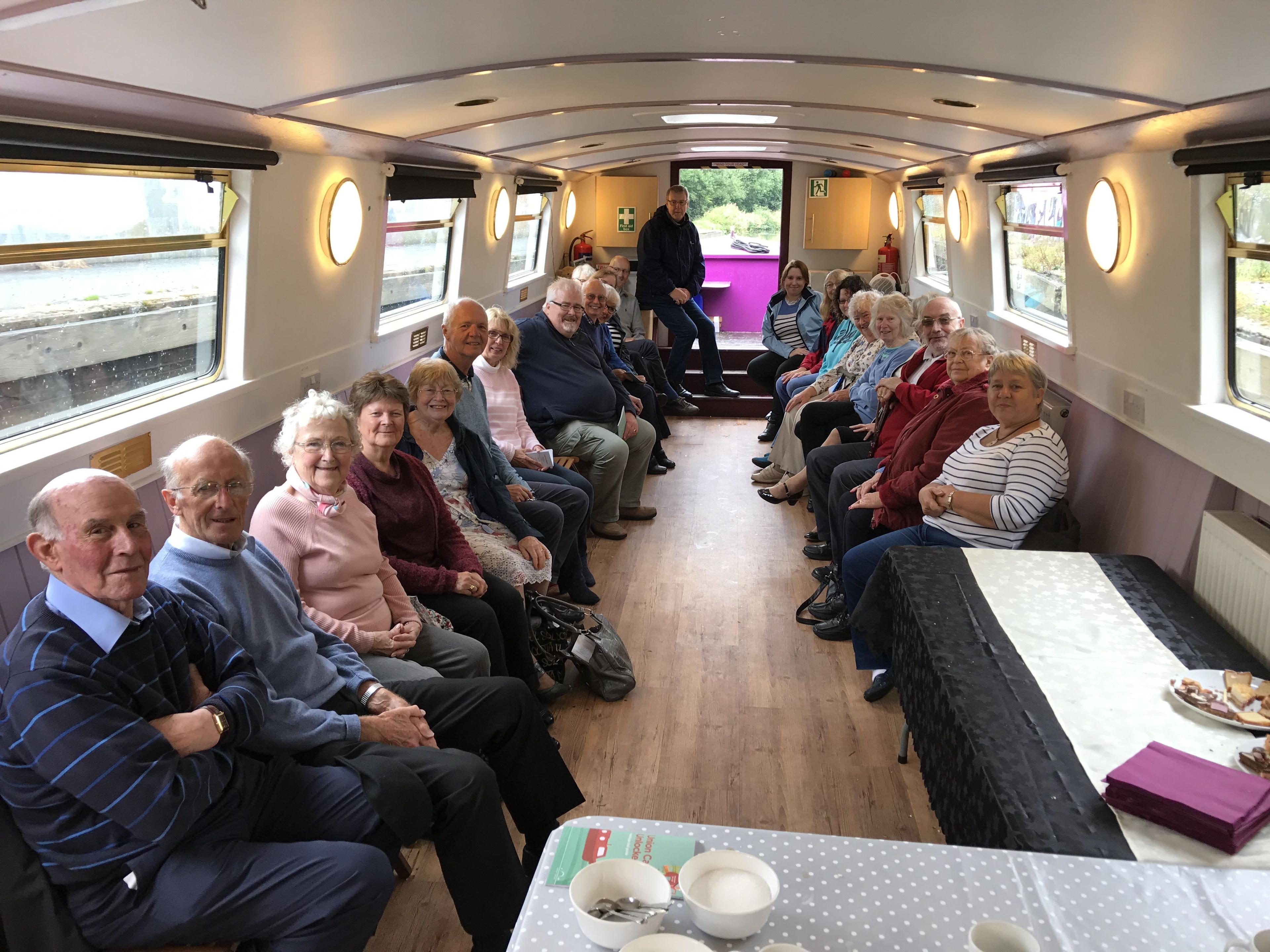 A group of people sitting along the walls inside a narrowboat