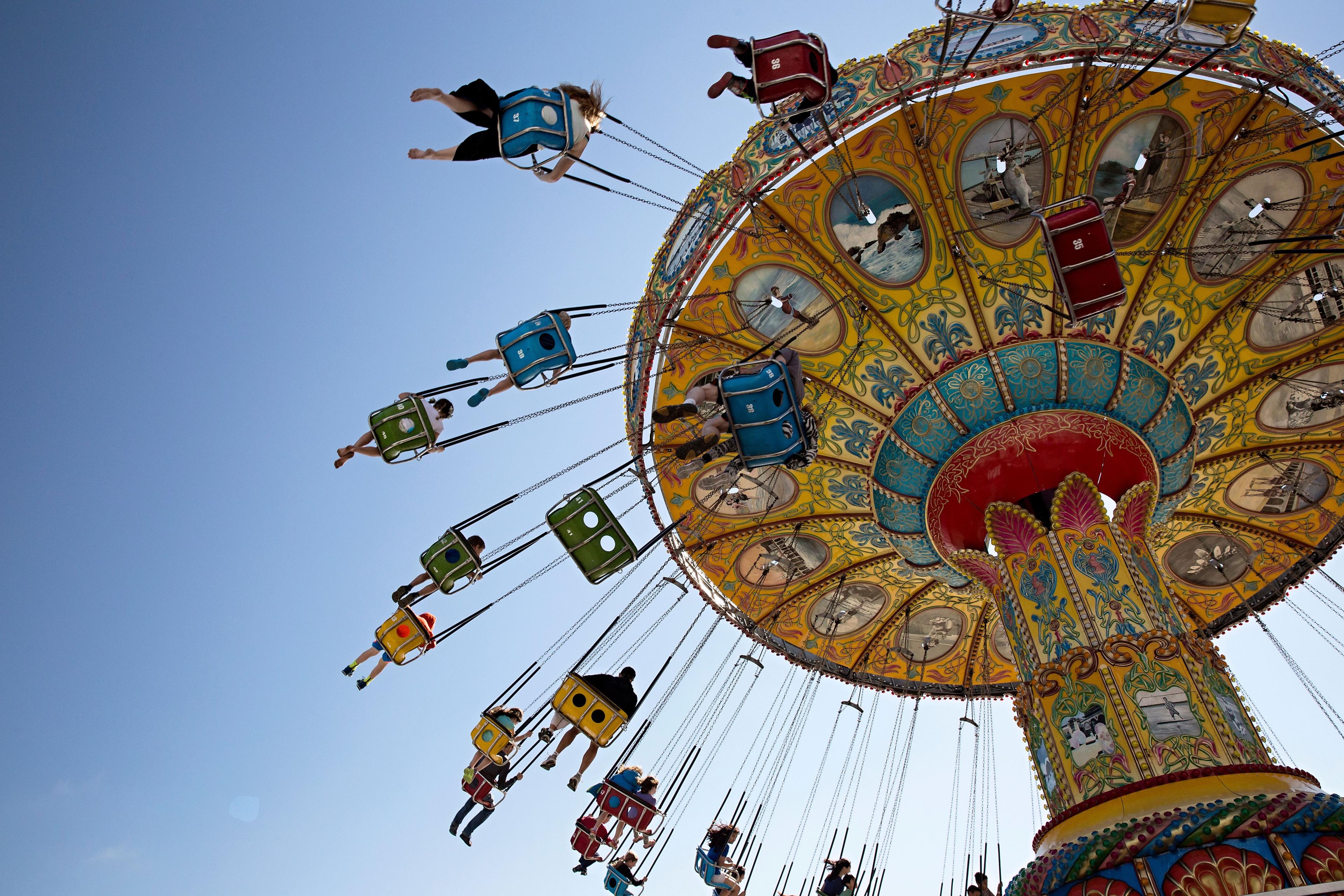 Colorful swing ride with people soaring high against a clear blue sky, showcasing vibrant designs and lively motion.