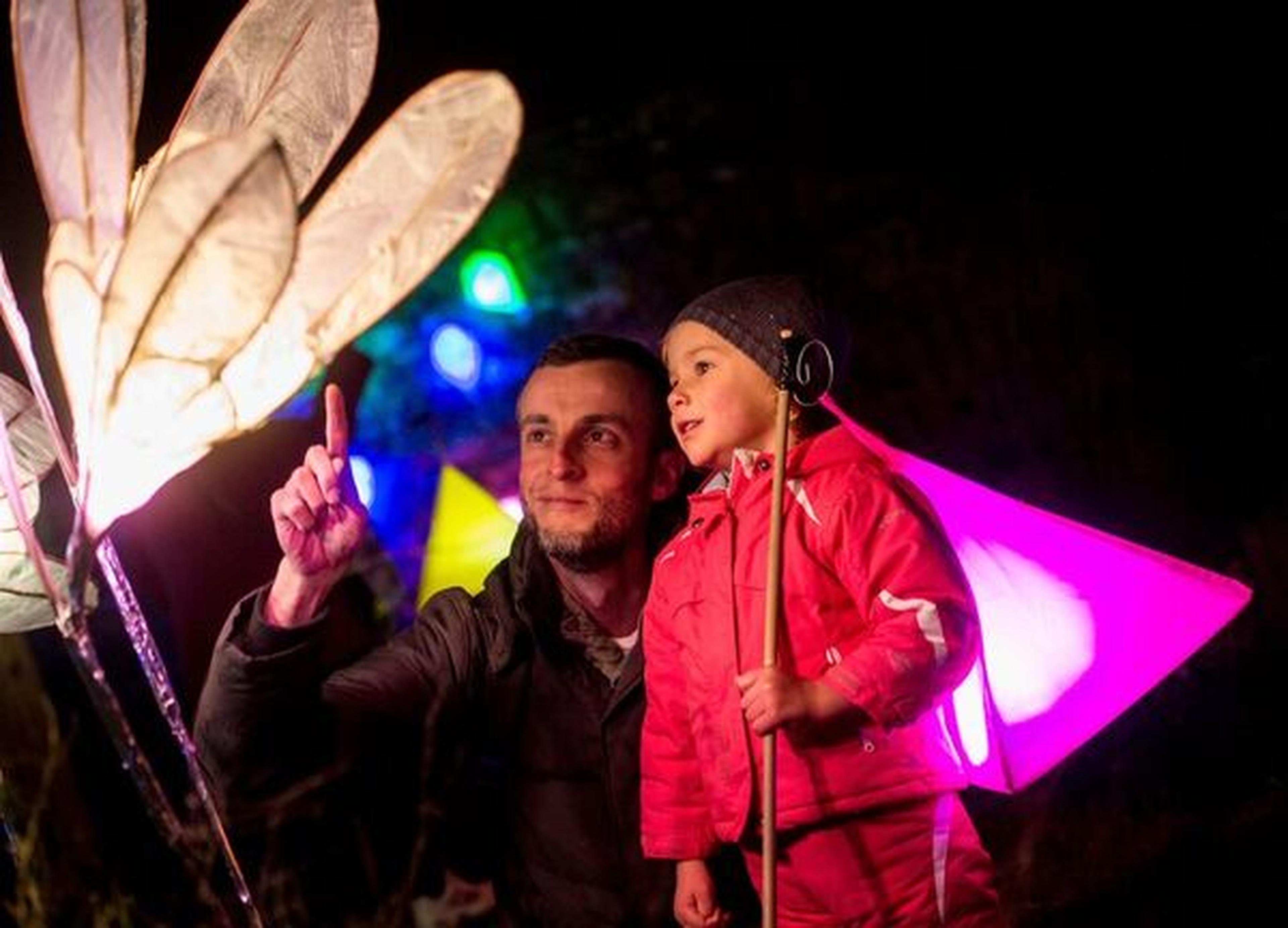 This photograph captures a family enjoying the illuminated lanterns at Glow Wild, a magical winter light trail at Wakehurst. The event features hundreds of handmade lanterns and torches that transform the forest into a glowing wonderland for visitors of all ages.