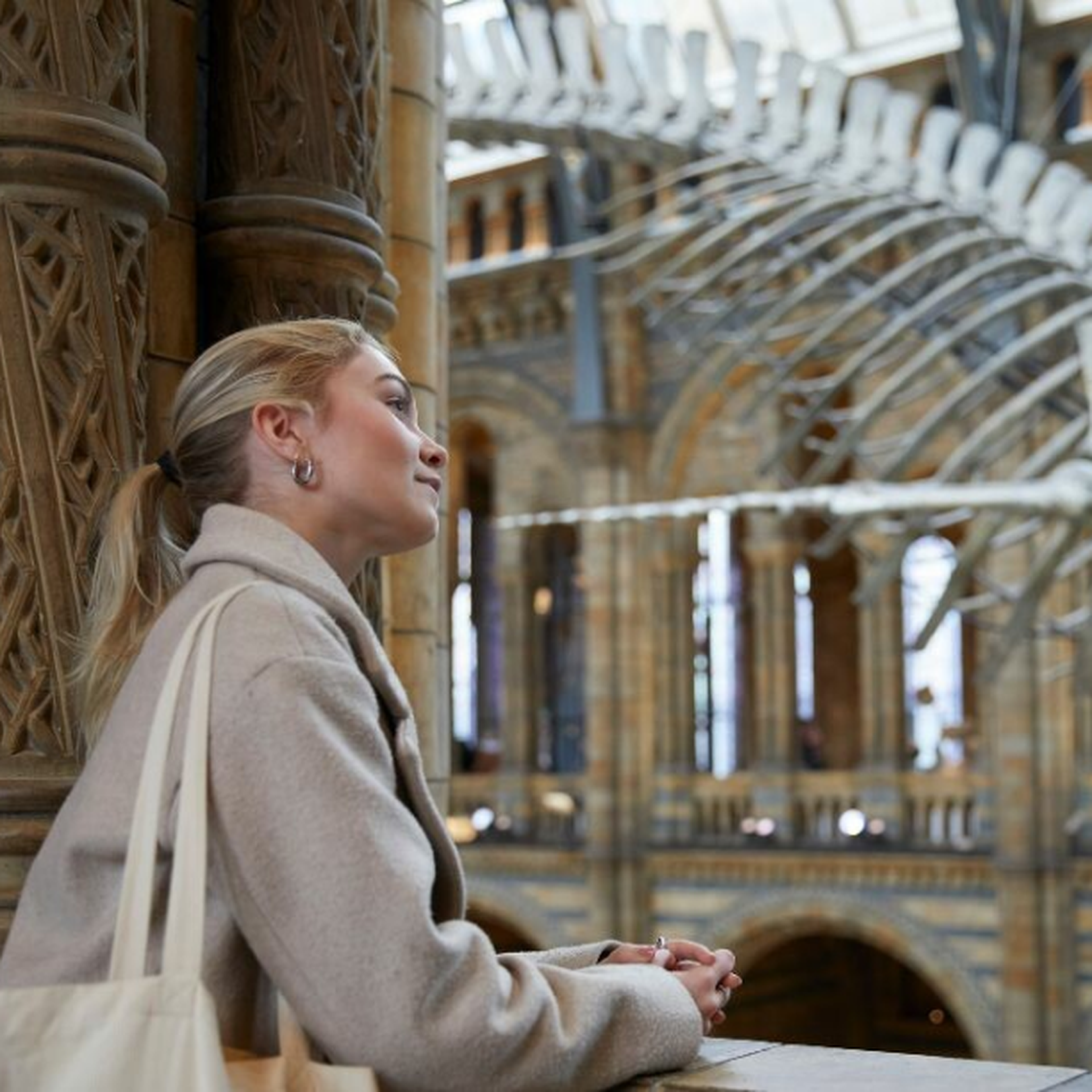 Woman looking at a dinosaur skeleton at the Natural History Museum