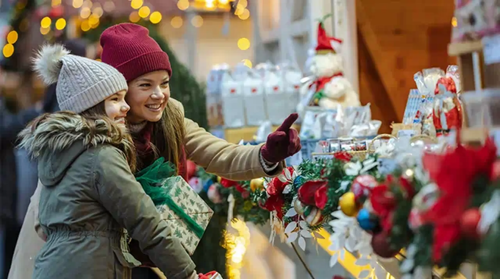 Adult and child in winter clothing shopping at a festive market stall
