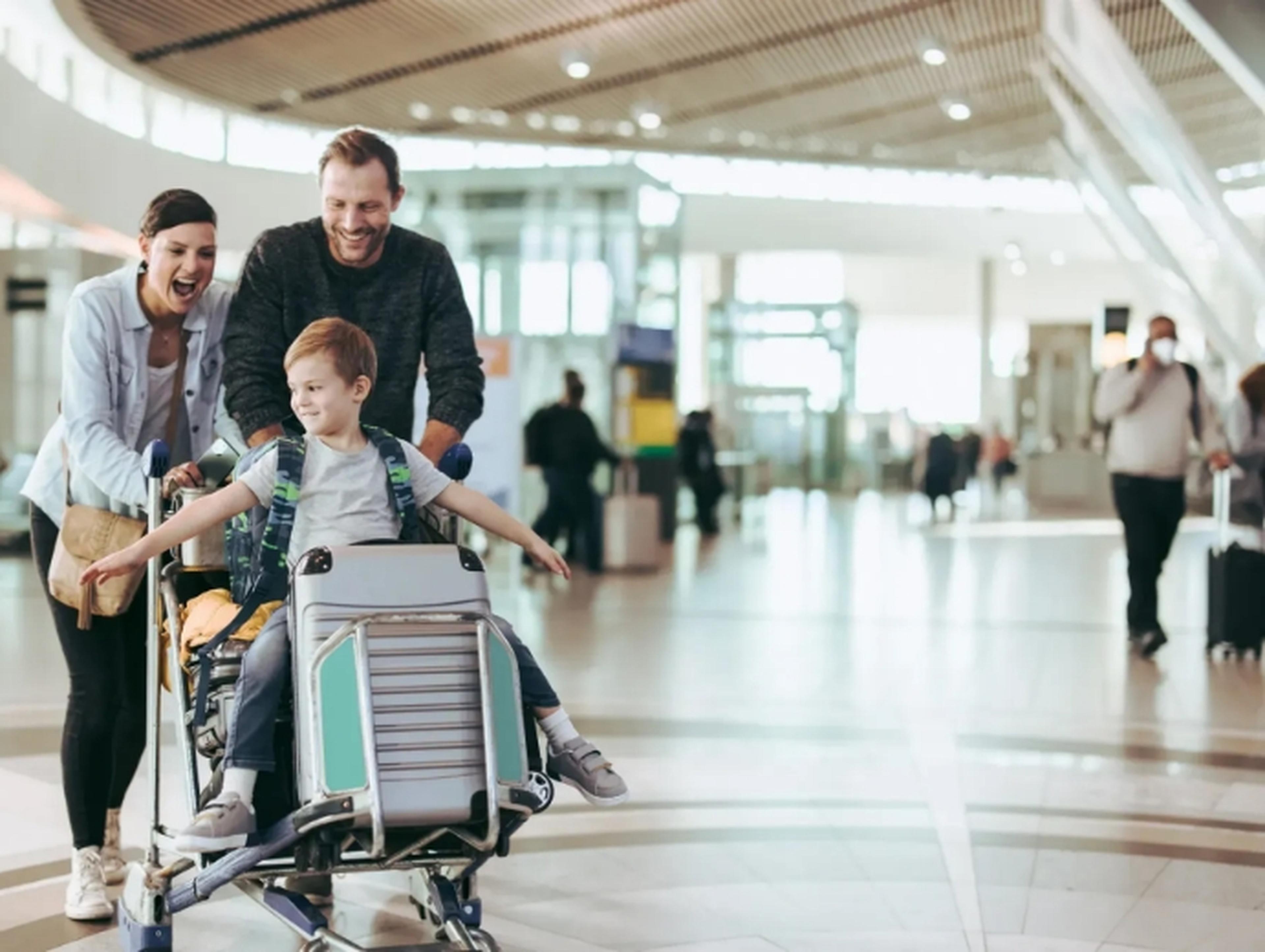 Family with child pushing a luggage trolley at the airport