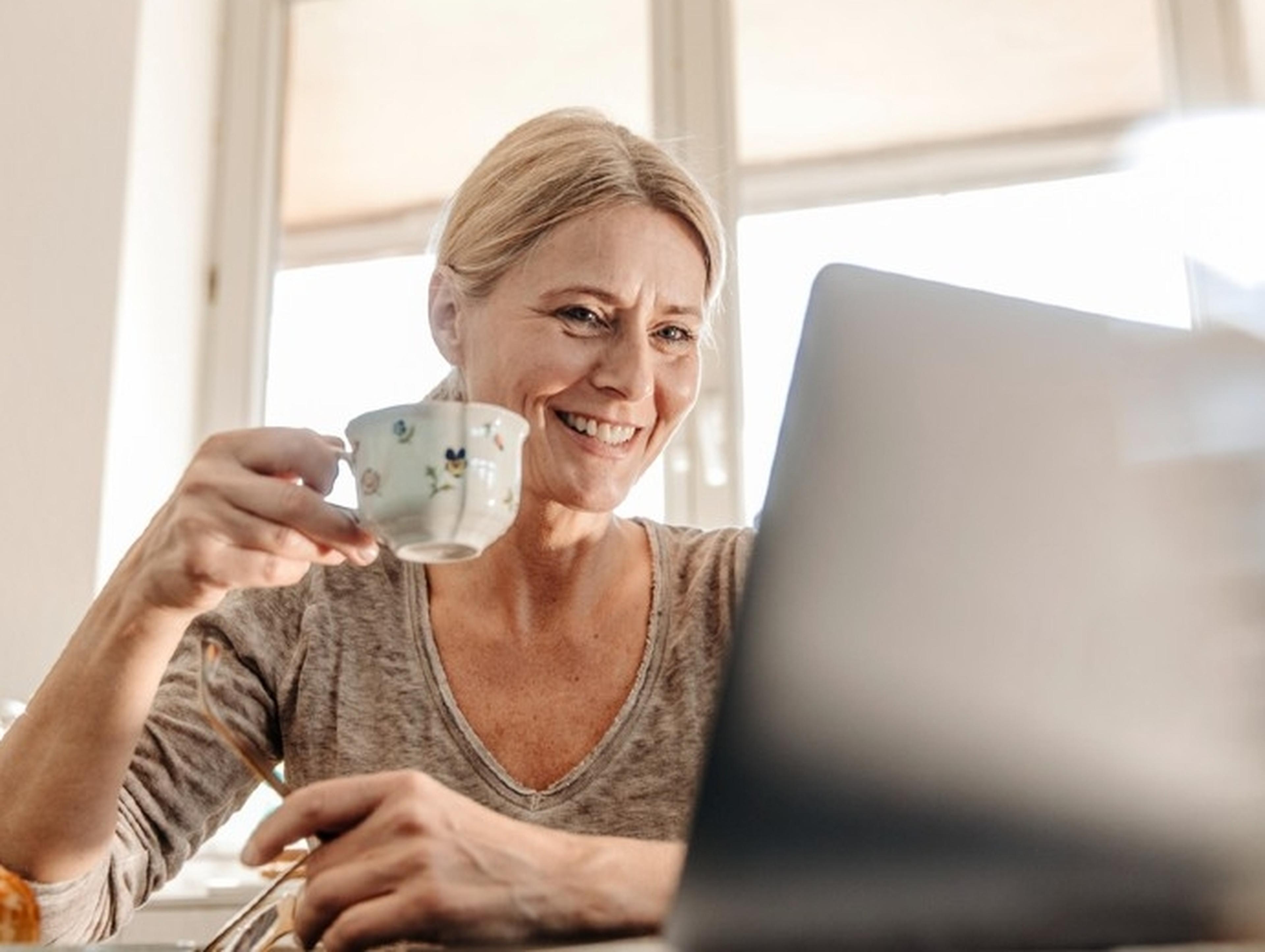Woman drinking tea whilst looking at her laptop