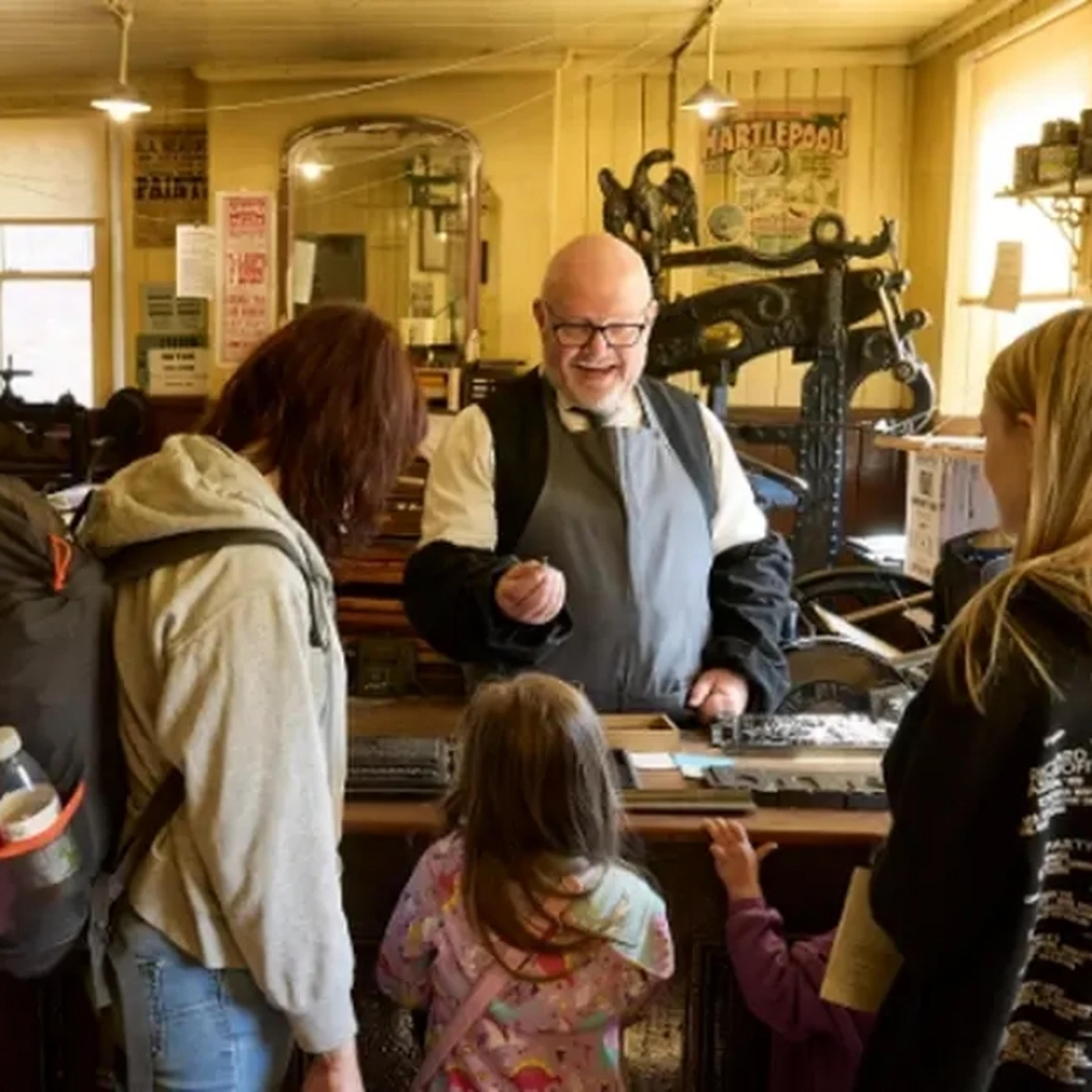 Family speaking to a man with a printing press