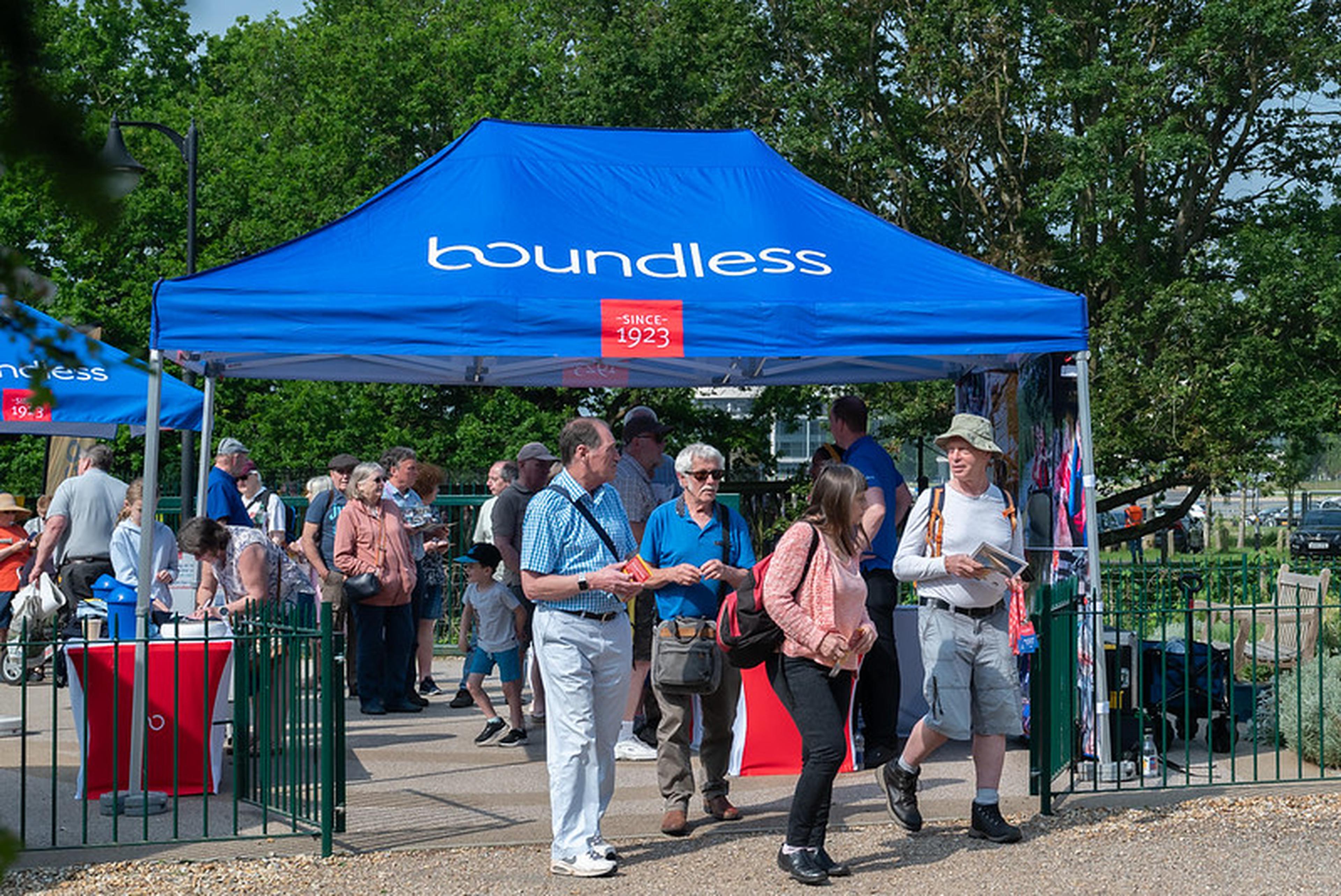 People gather under a blue "boundless" tent at an outdoor event.