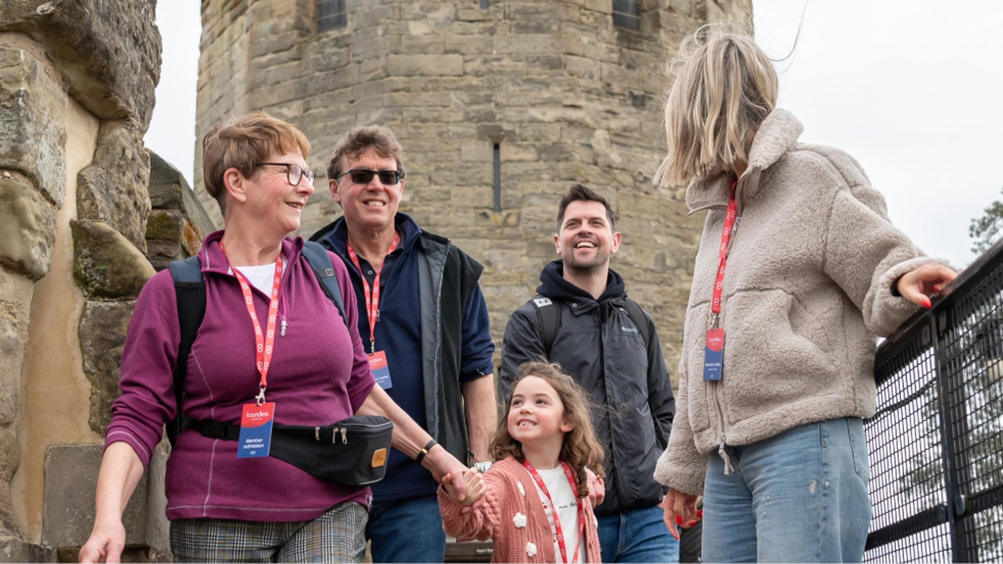 A family group smiles and explores a historic stone castle