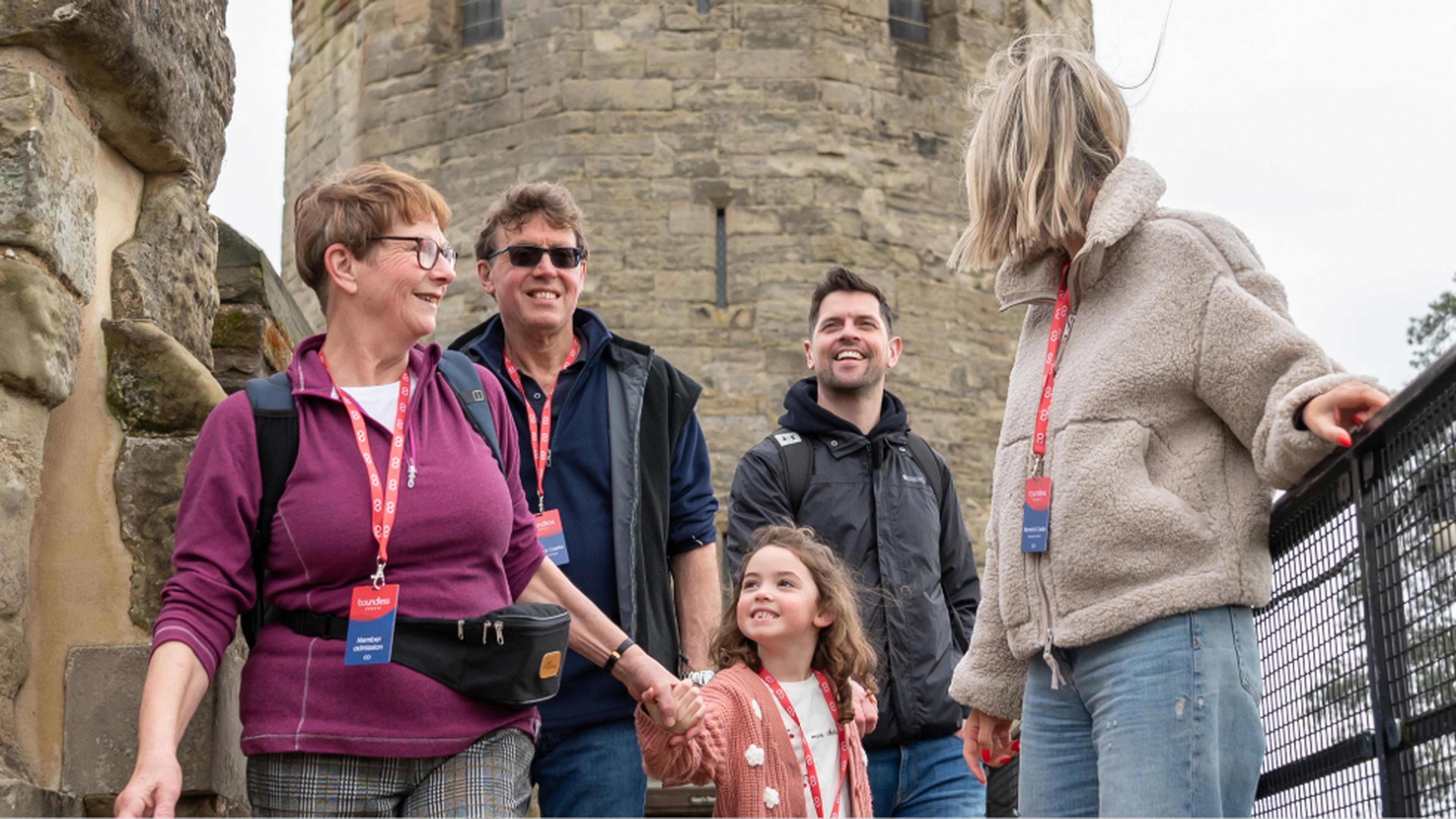 A family group smiles and explores a historic stone castle