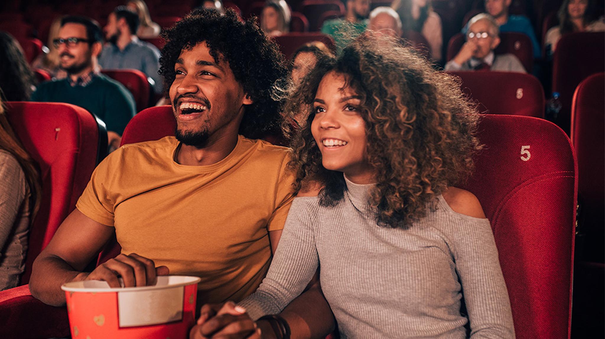 A couple in a cinema theatre with popcorn