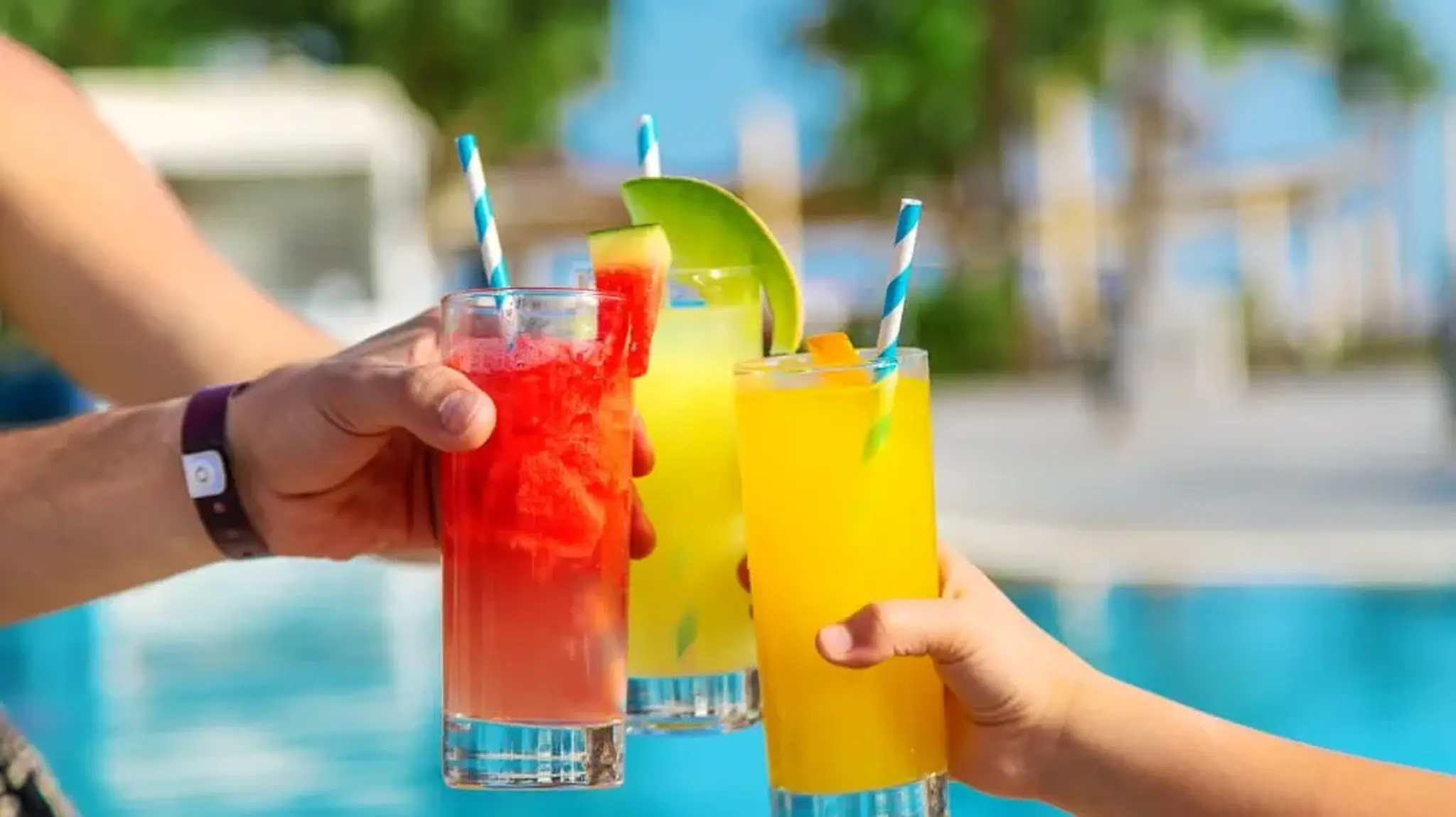 Three colorful tropical drinks with striped straws
