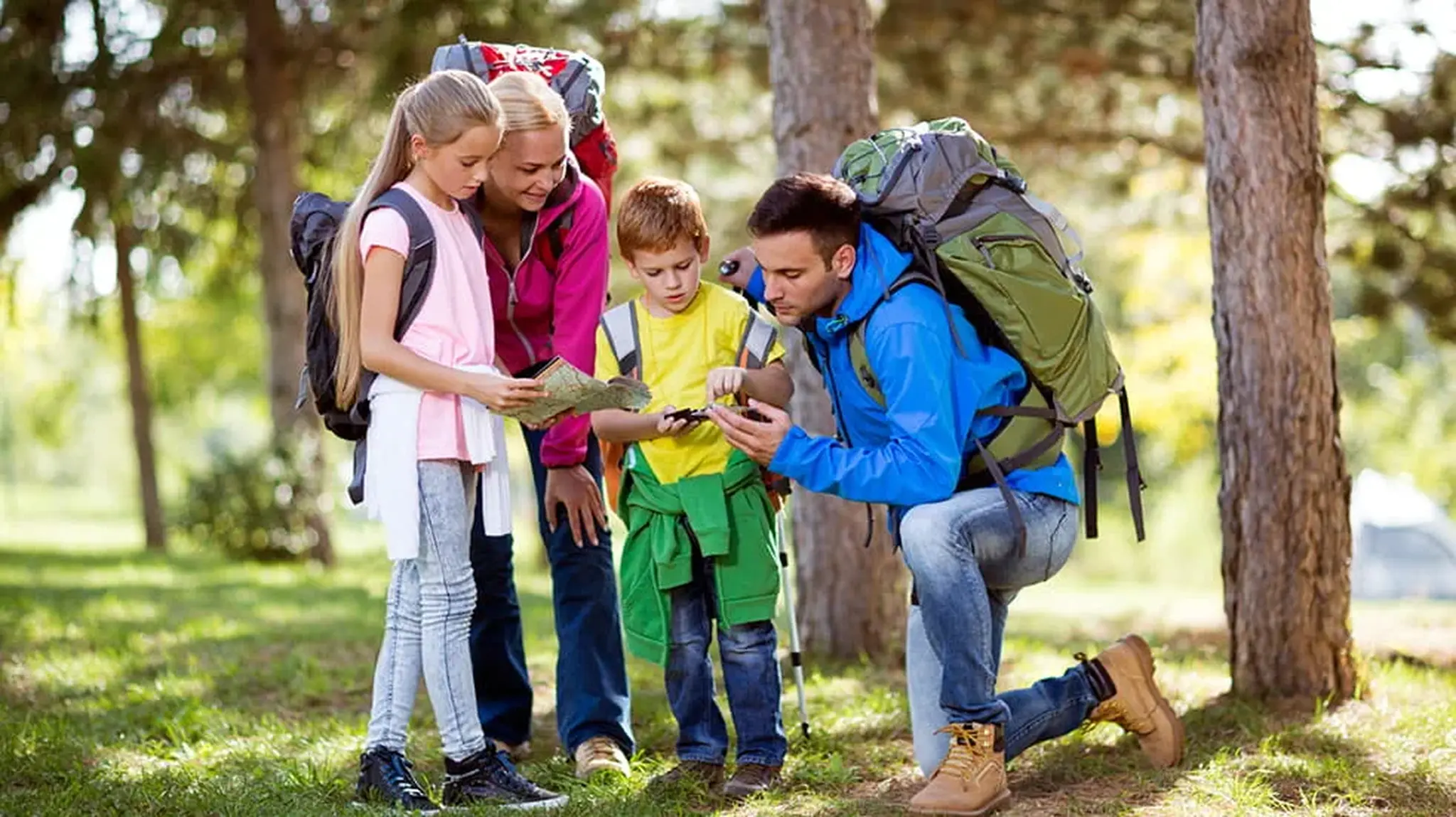 Family hiking in a forest, two adults and two children looking at a map