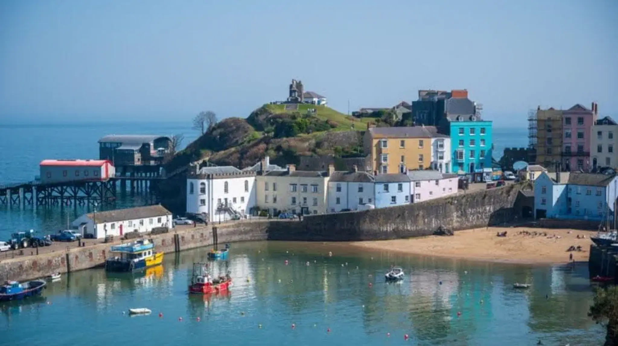 Colorful seaside town with pastel buildings and a harbour filled with boats in South Wales