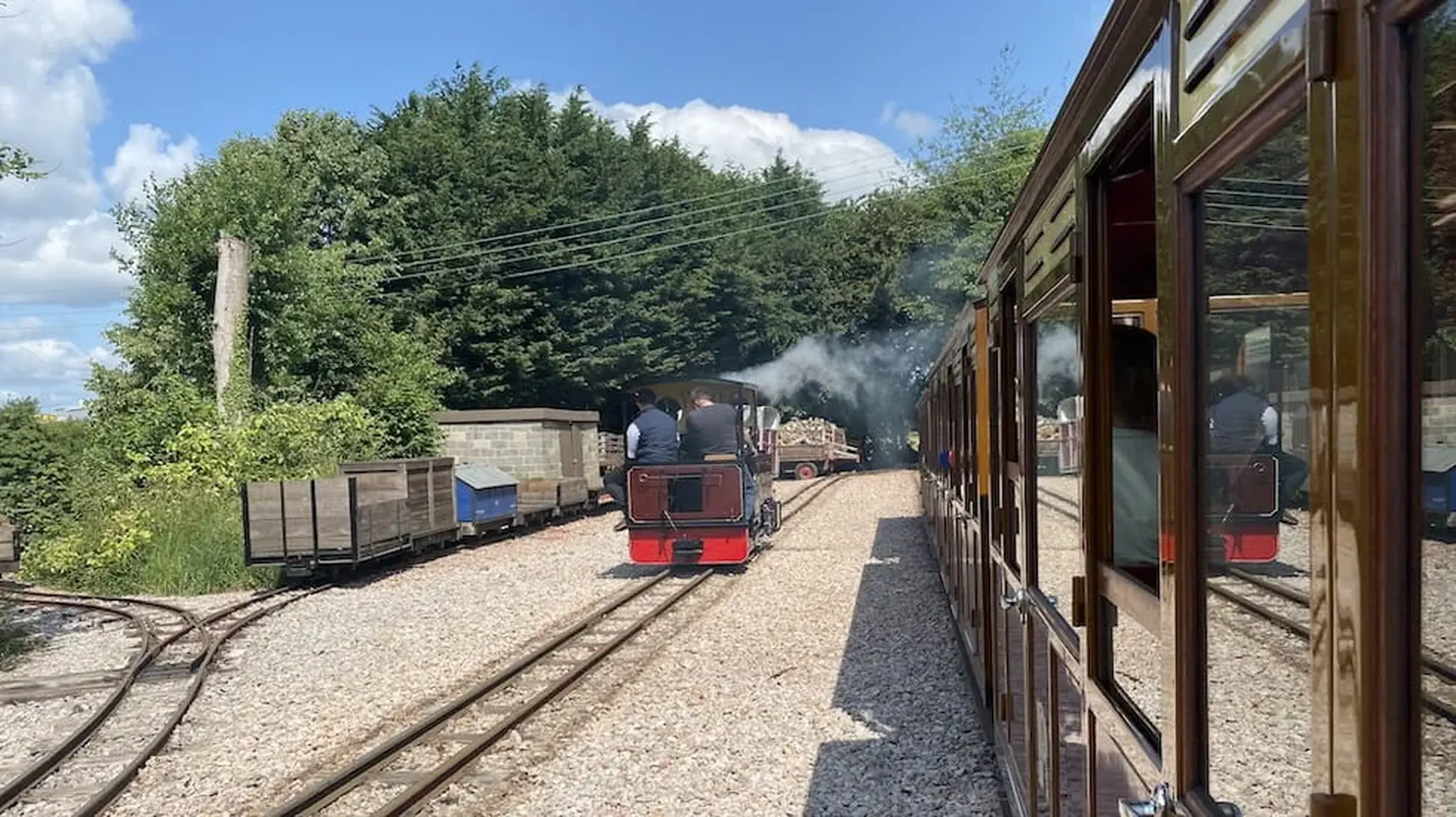 A narrow-gauge train travels on a sunny day