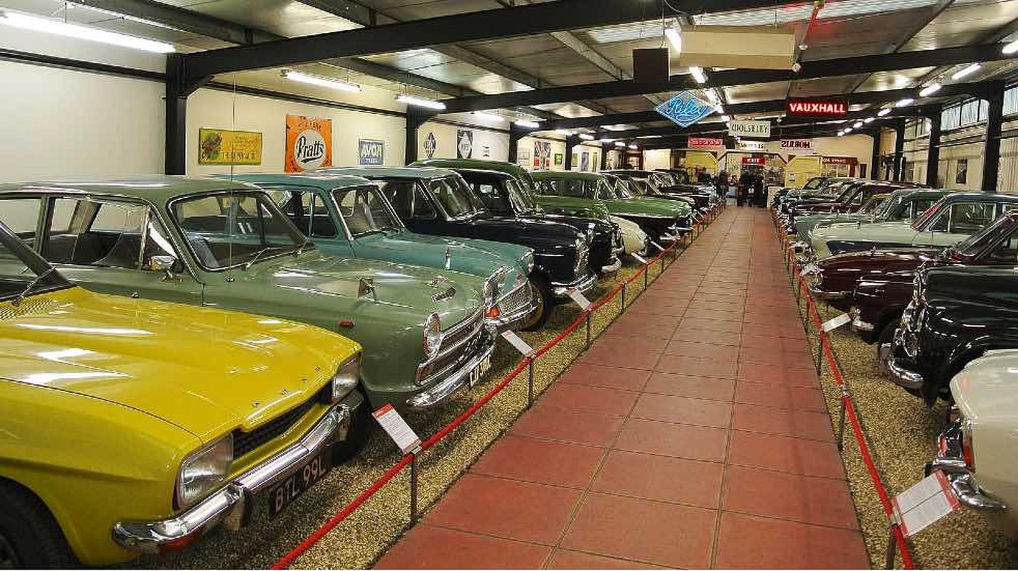 A row of vintage cars in various colors displayed in the Haynes Motor Museum