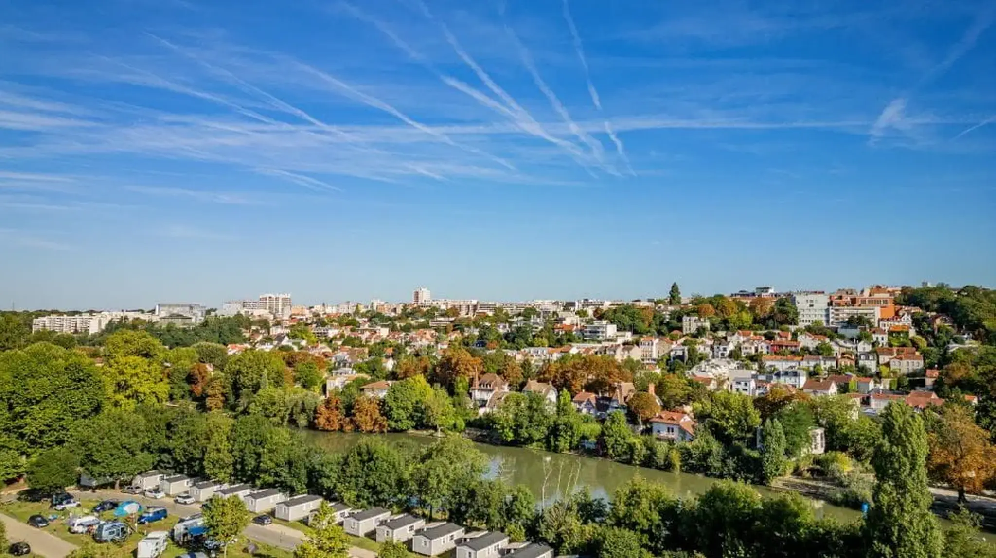 Aerial view of a suburban area with a river, surrounded by trees and houses