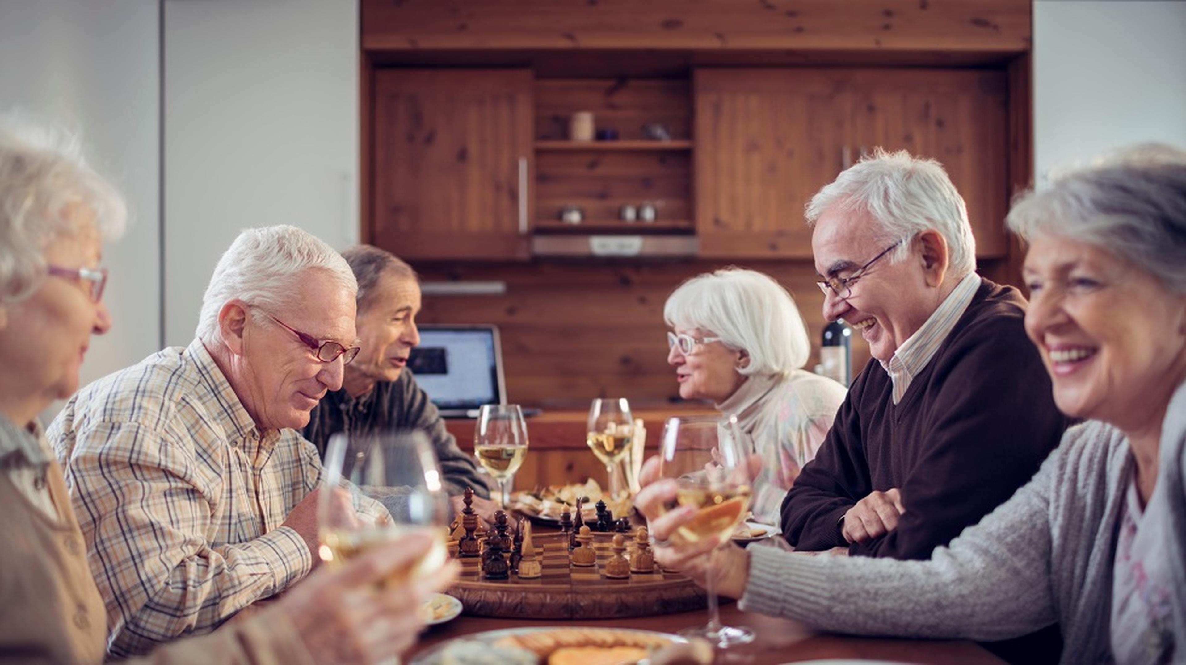 A group of elderly friends enjoying a chess game and glasses of wine