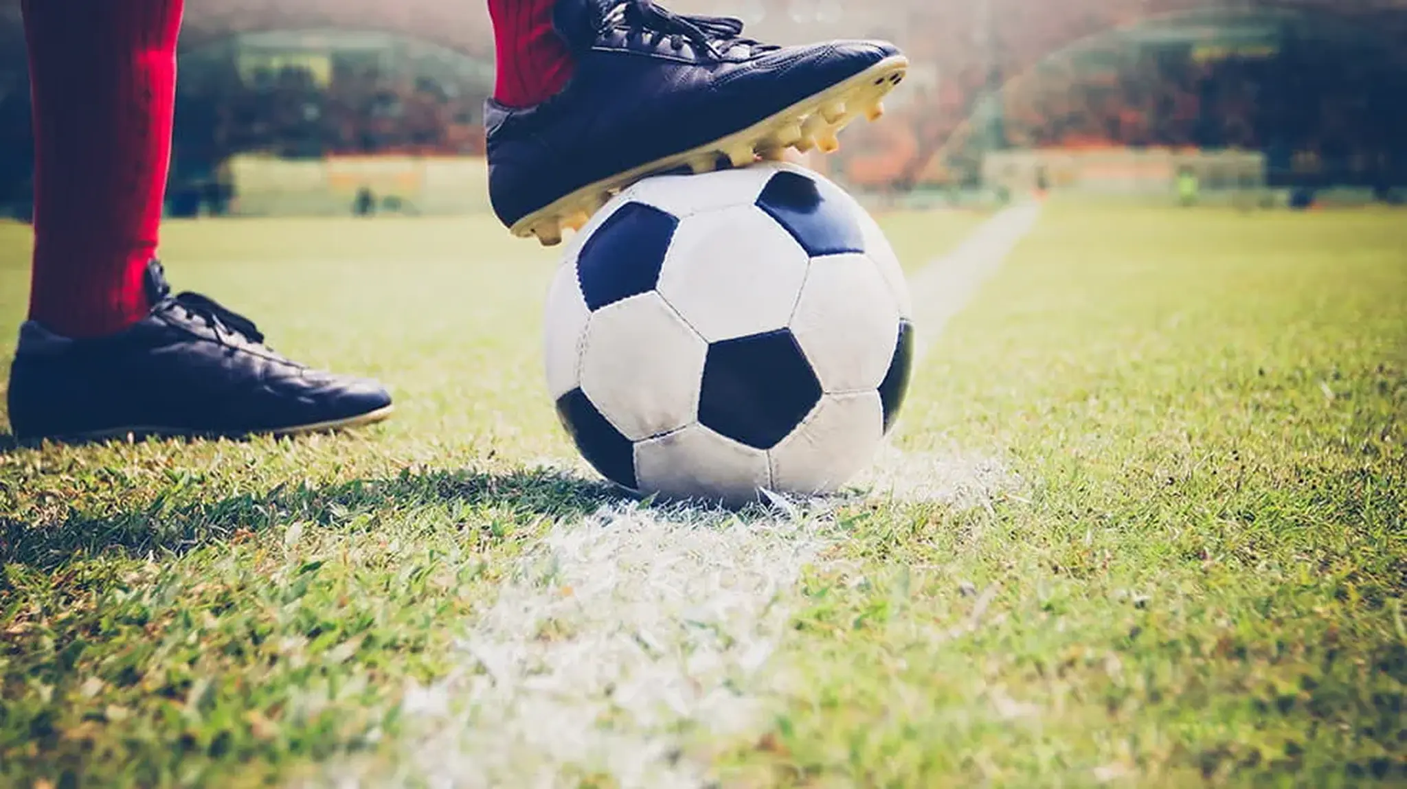 A football player standing on a green field, resting one foot on a football