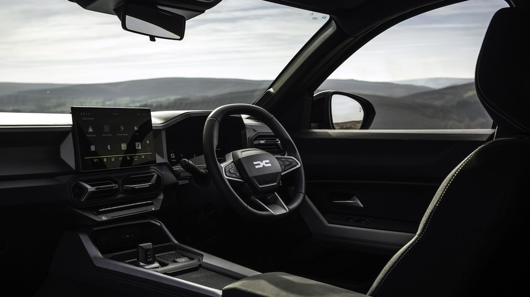 Modern car interior with a sleek dashboard and steering wheel, featuring a digital display with scenic hills visible through the windshield.