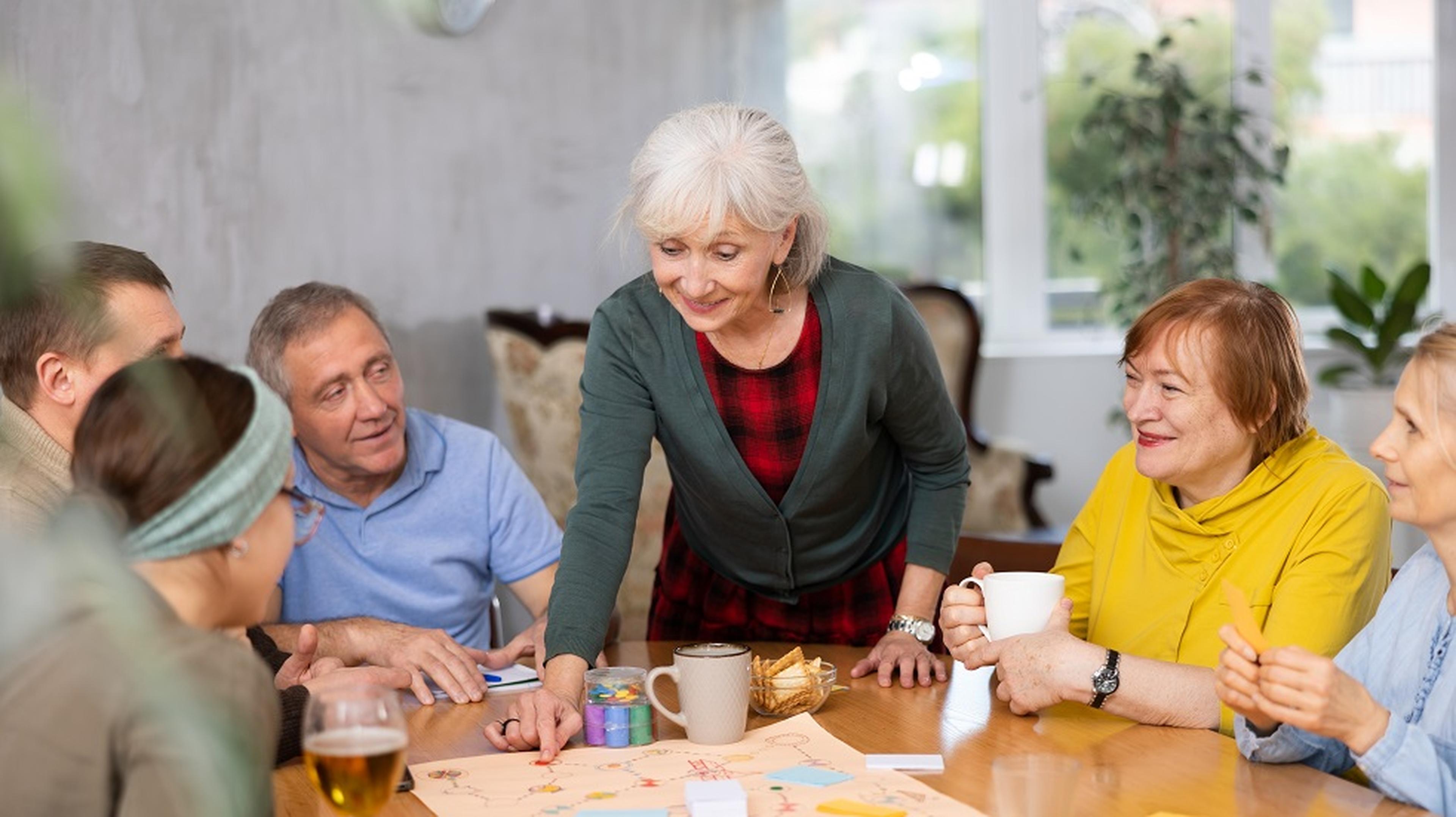A group of people, including an elderly woman, happily playing a board games