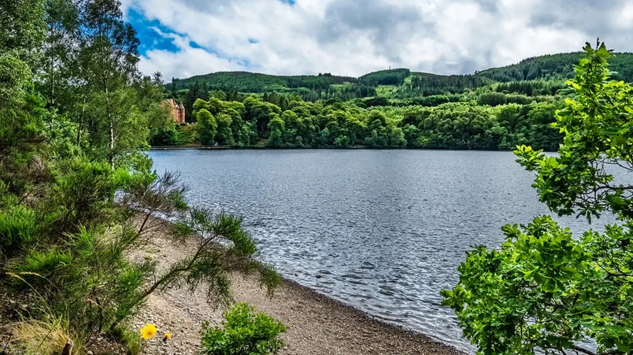 Serene lake surrounded by lush green hills and trees