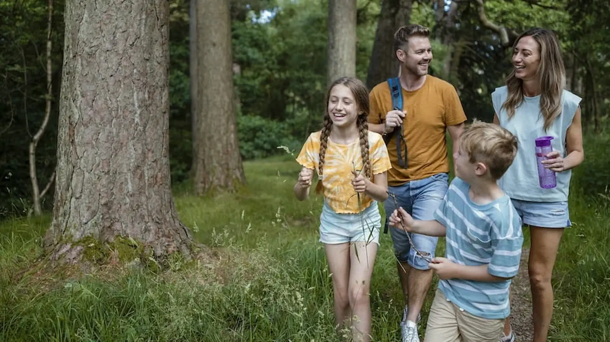 A family of four enjoys a walk in a forest