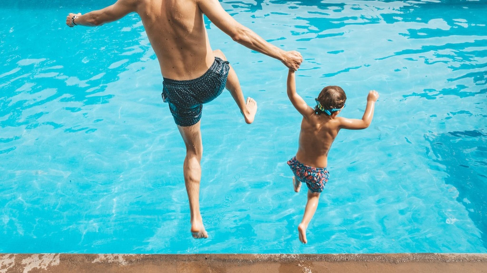 Father and son jumping in pool