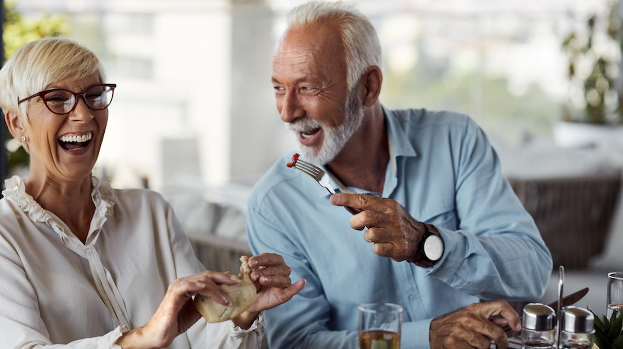 A man and lady laughing whilst dining