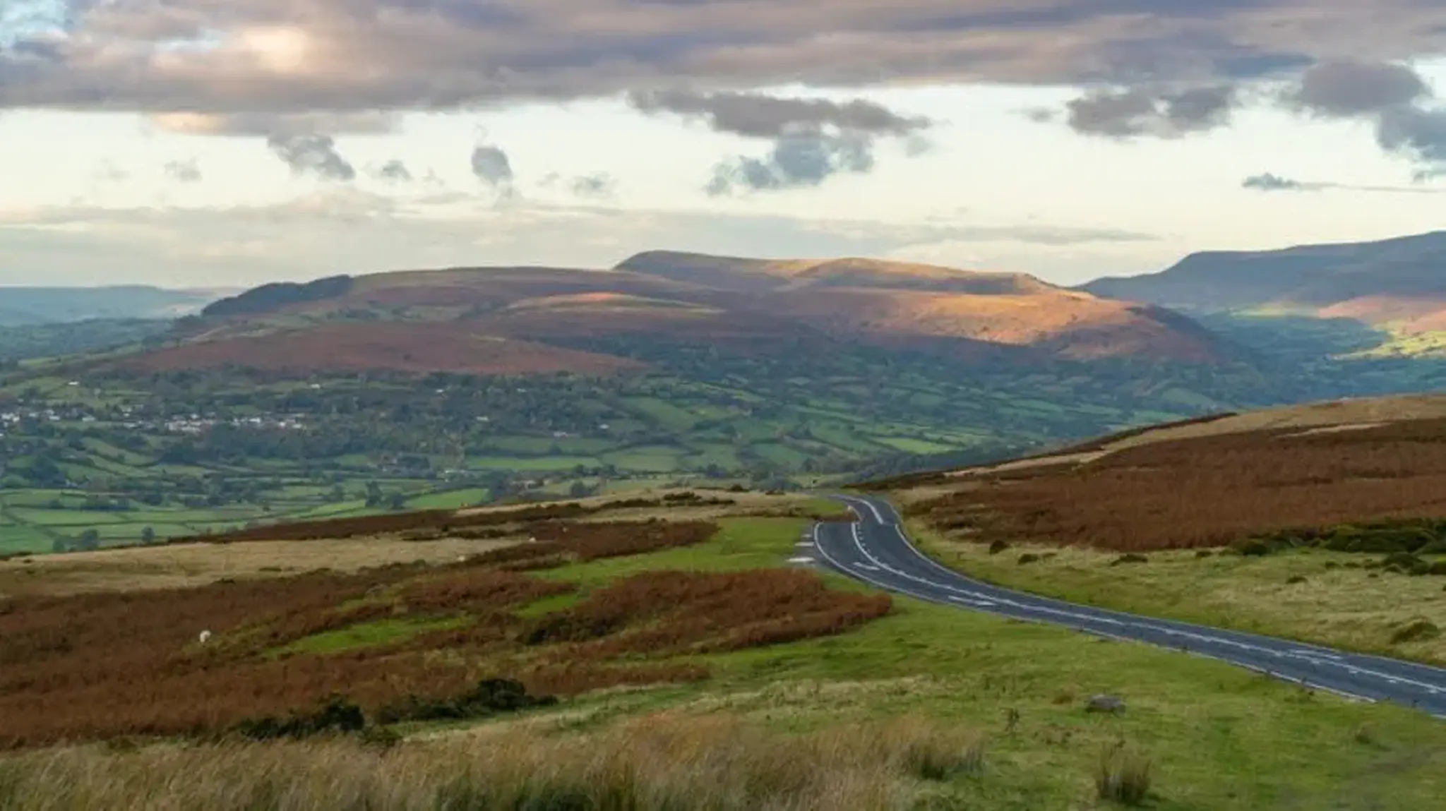 Scenic view of a winding road through a grassy landscape with distant hills