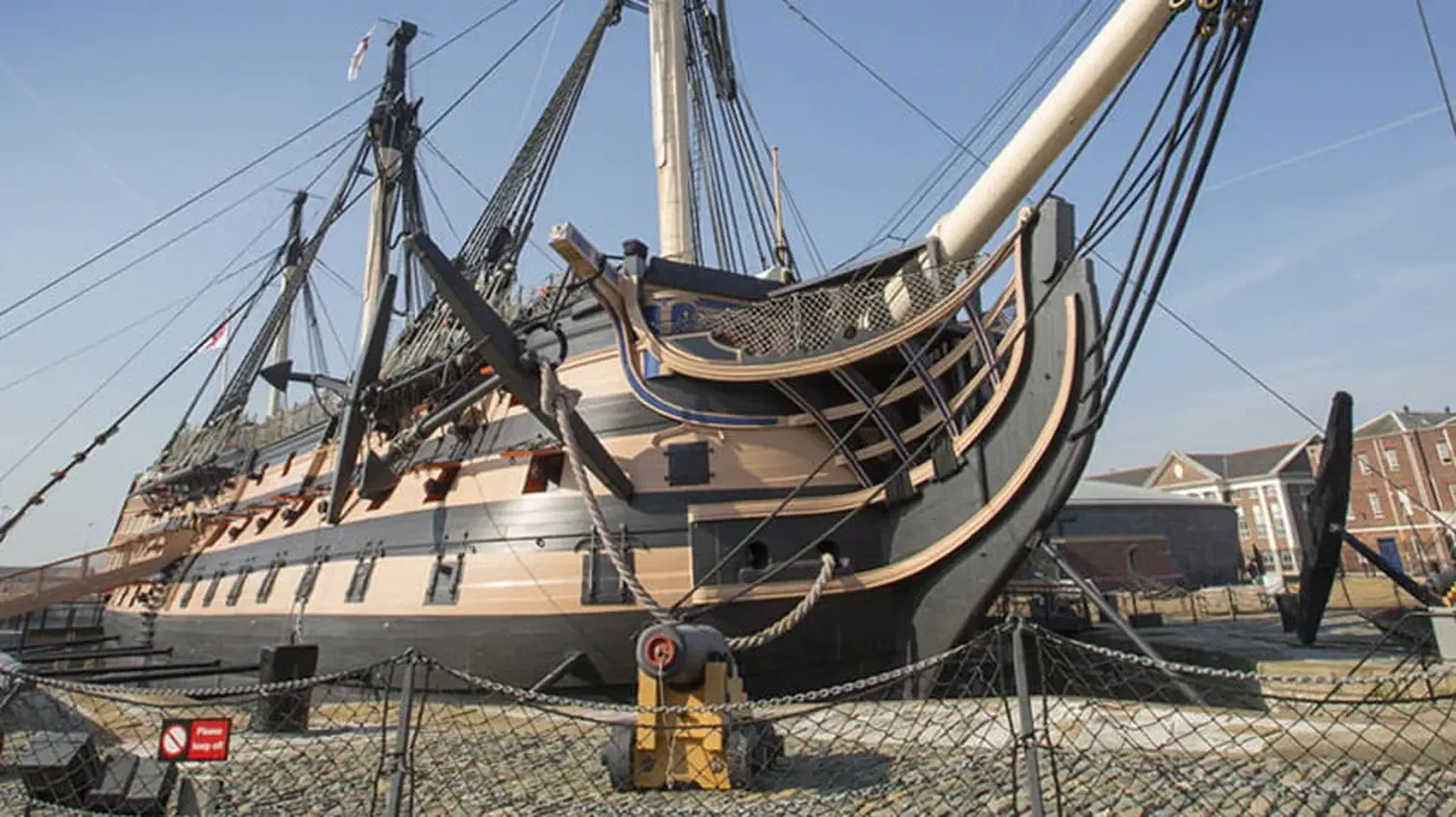 Historic sailing ship with black and beige hull, docked.