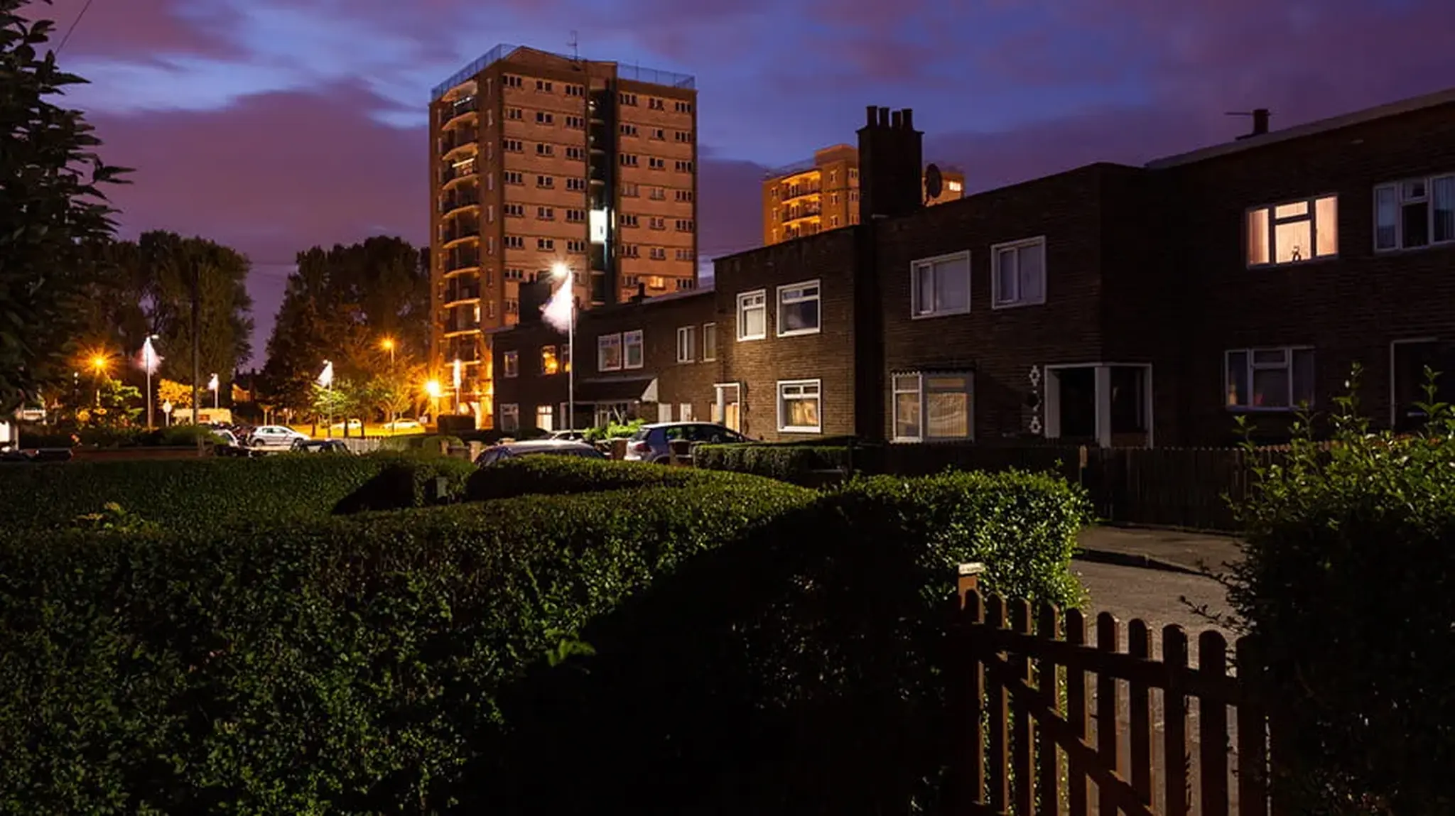 Residential street at dusk with lit windows