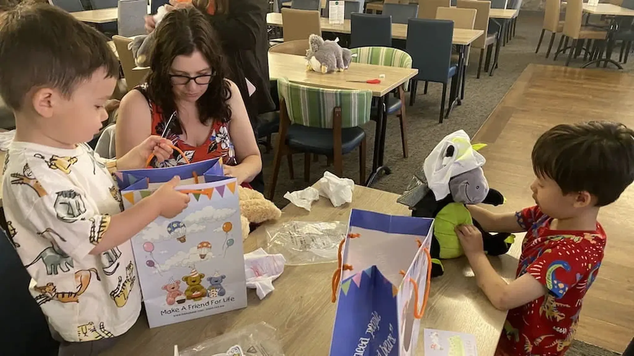 Two young boys and a woman sitting at a table, assembling toys