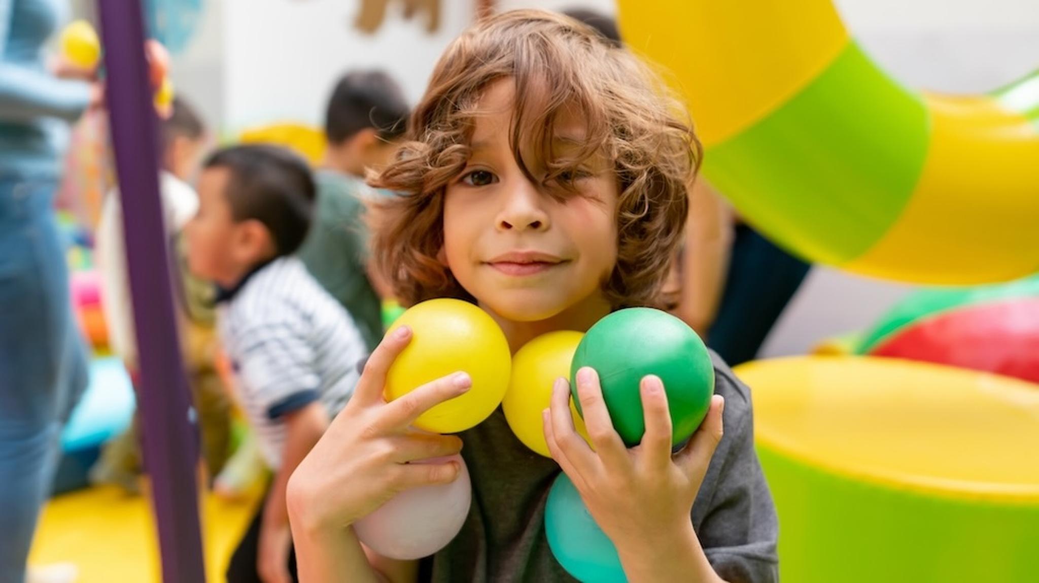 Little boy smiling and holding 5 balls