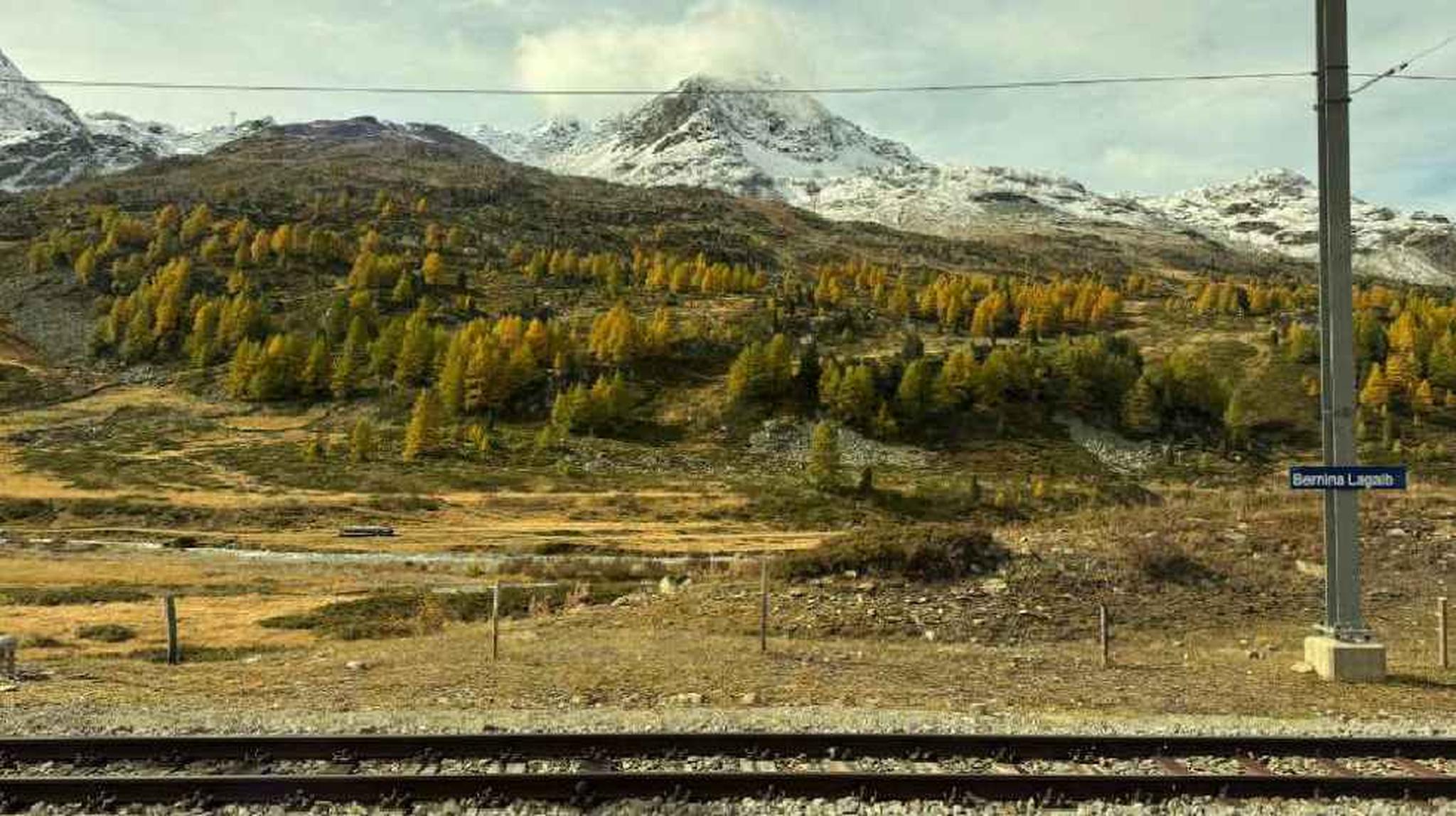 Railway tracks leading to snow-capped mountains with a sign that says "Bernina Lagalb."