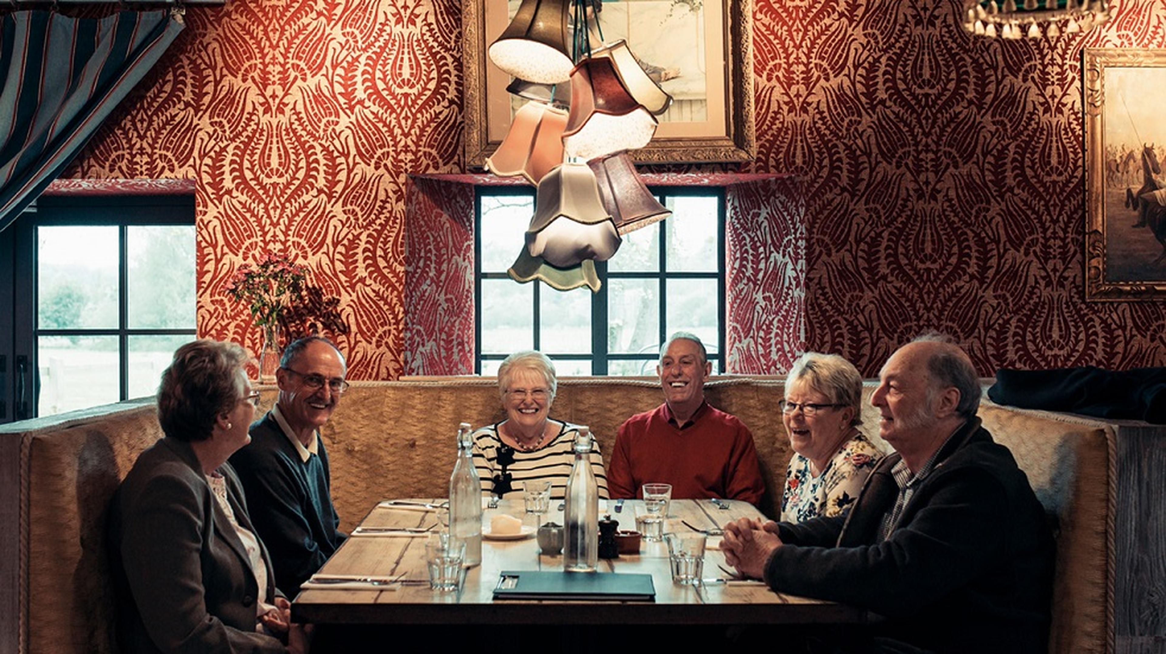 A group of people smiling and sitting around a wooden table