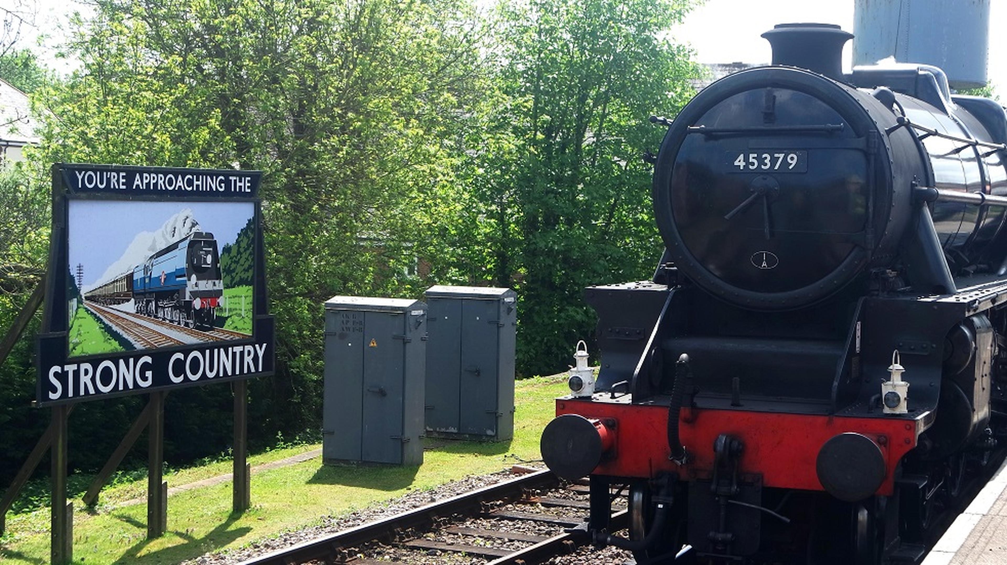 Steam locomotive 45379 at a station beside a sign reading "You're Approaching the Strong Country"