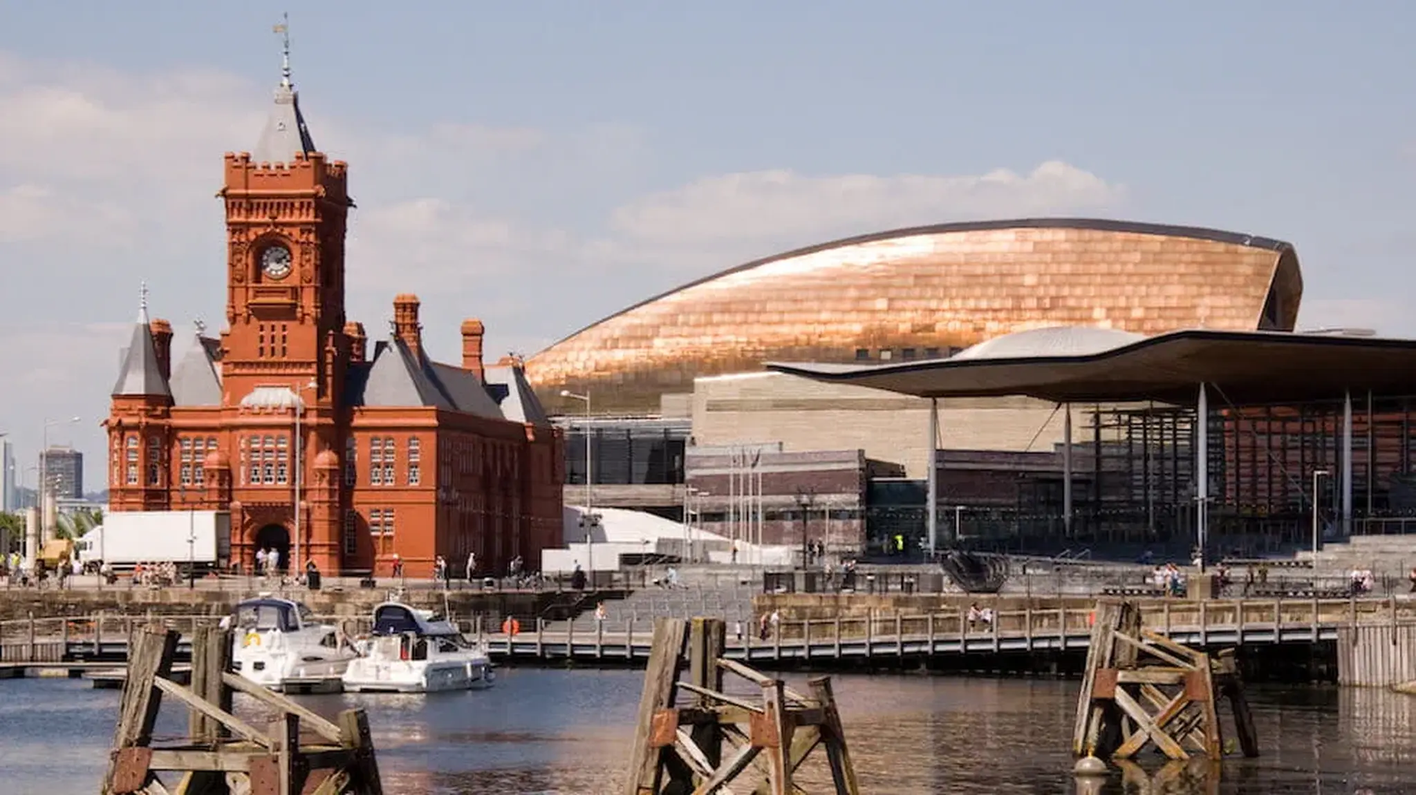 A waterfront view of the red-brick Pierhead building and bronze-roofed Wales Millennium Centre
