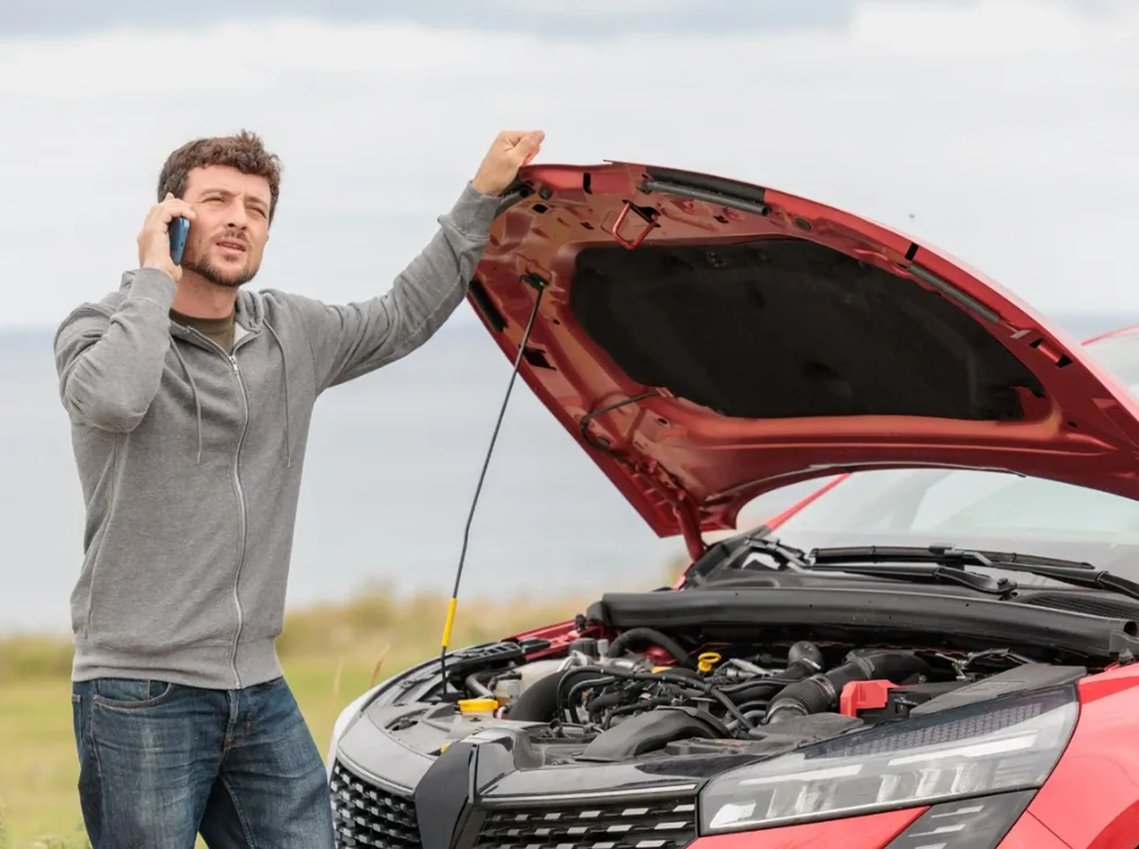 An iamge of a man standing by a broken down car