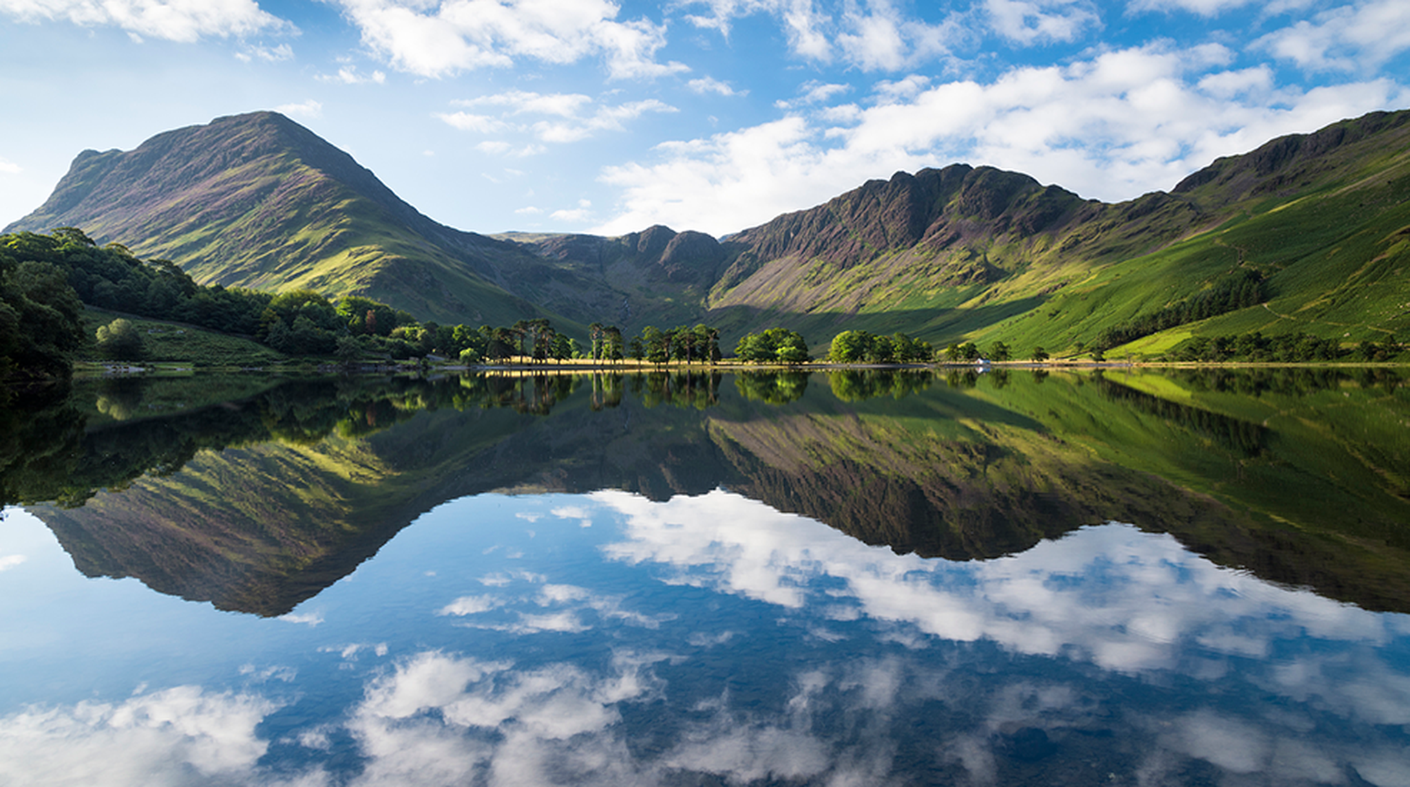 Buttermere lake early morning reflections. A beautiful summer morning with Fleetwith Pike and Haystacks mountains covered in purple heather. L