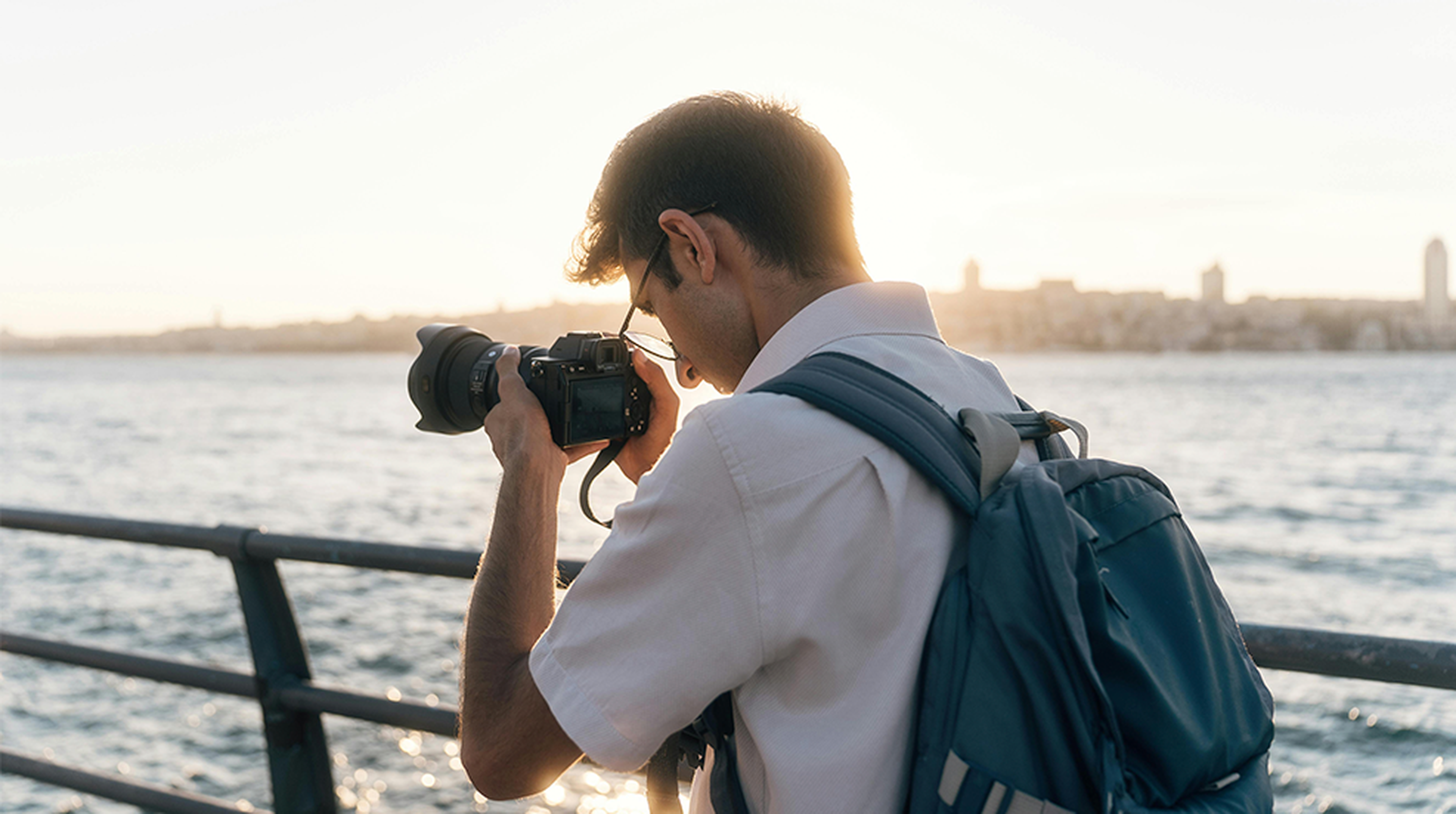A male photographer captures stunning shots by the waterfront during sunset.